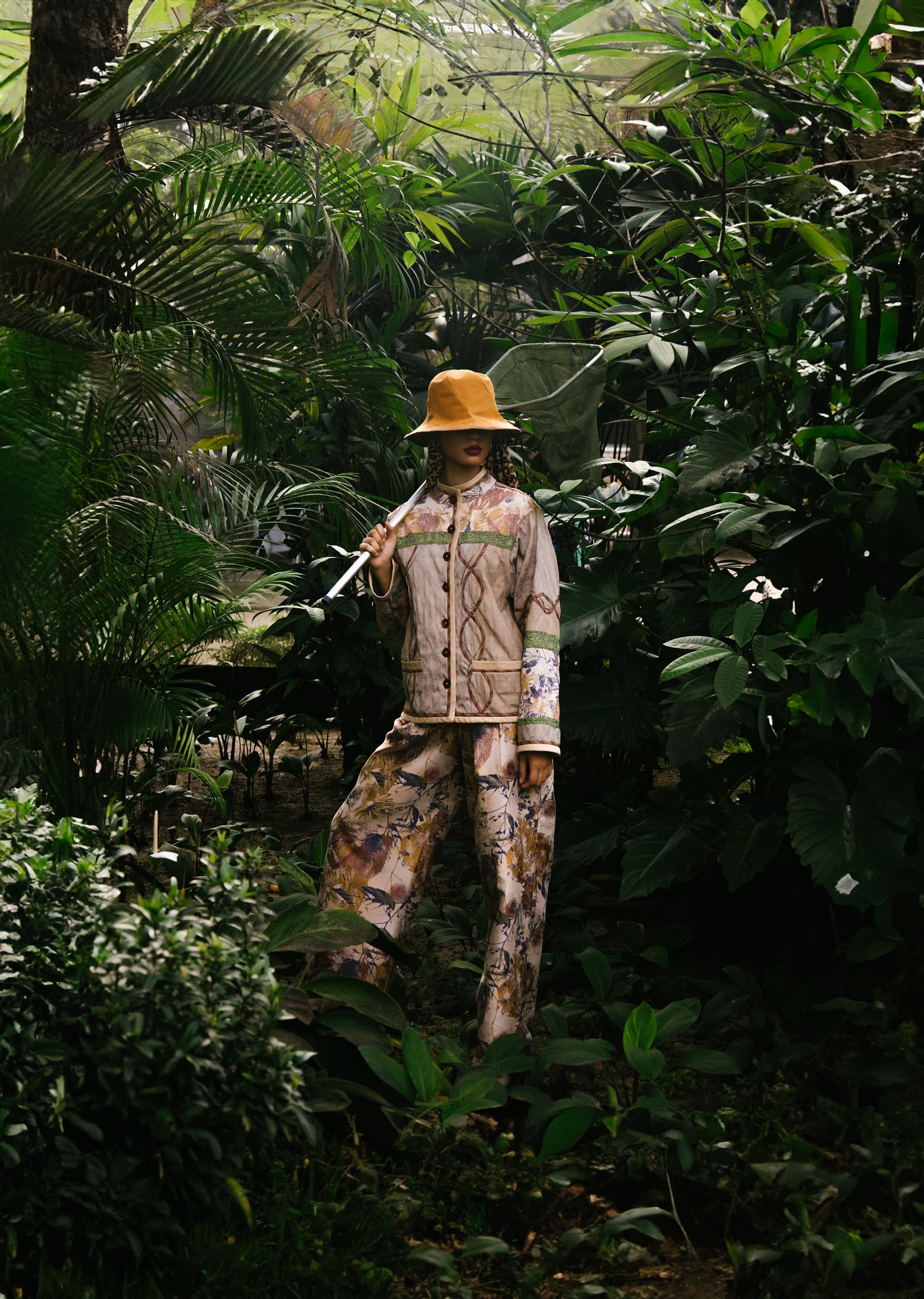Person in stylish outfit and hat exploring lush green jungle environment