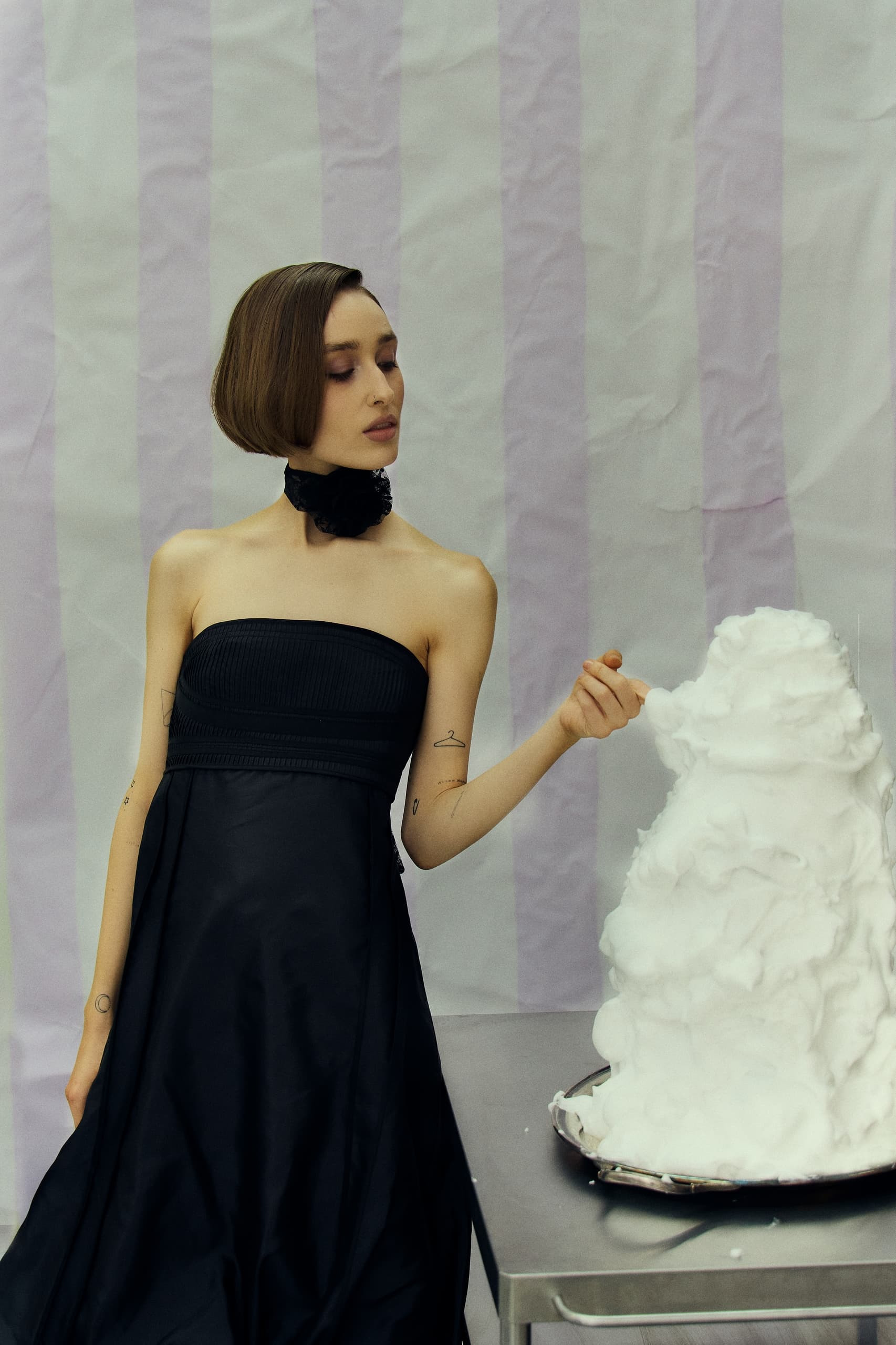 Woman in black dress interacts with a sculpture on a table.