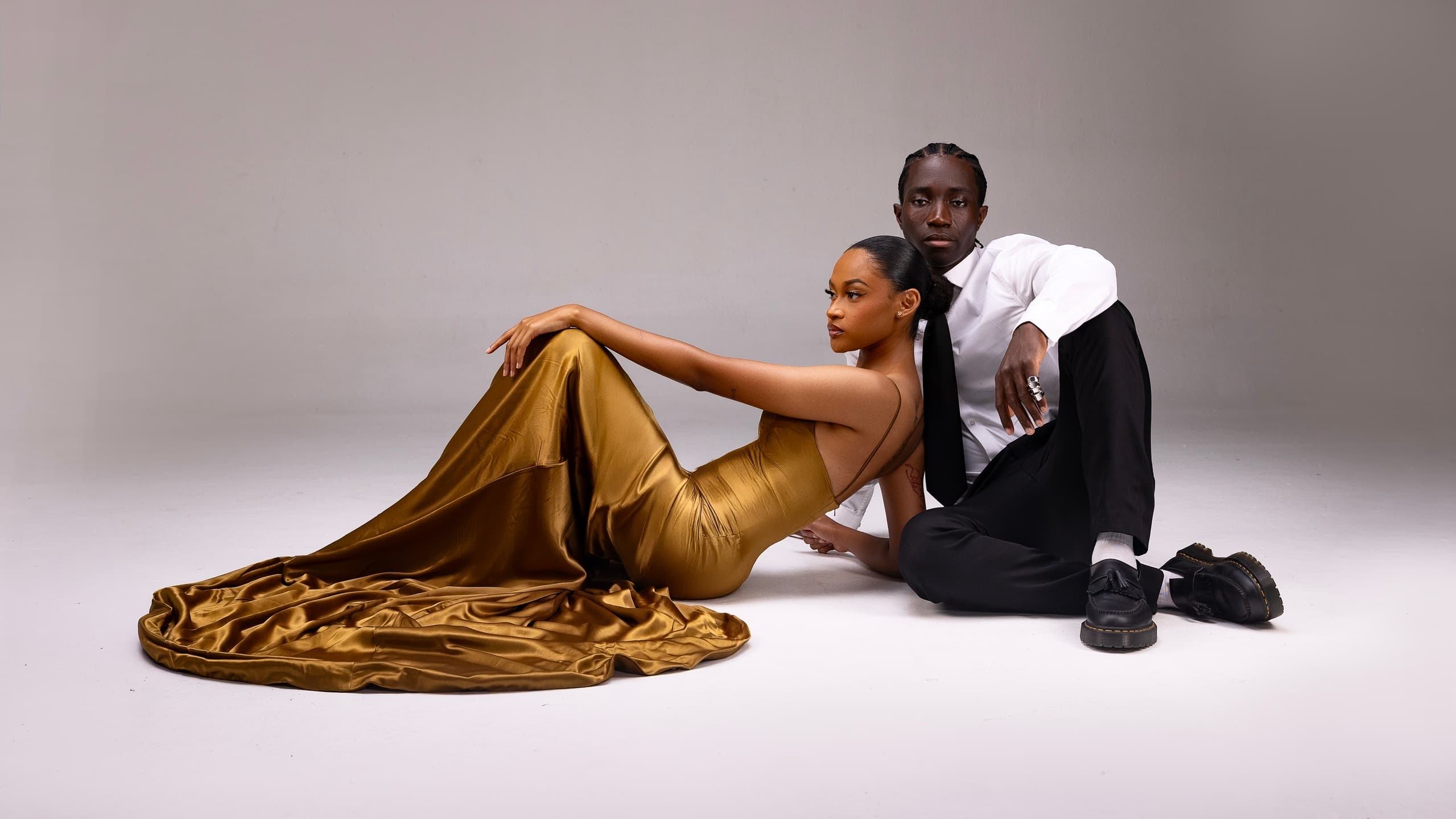 Elegant couple in stylish attire posing in a studio setting.