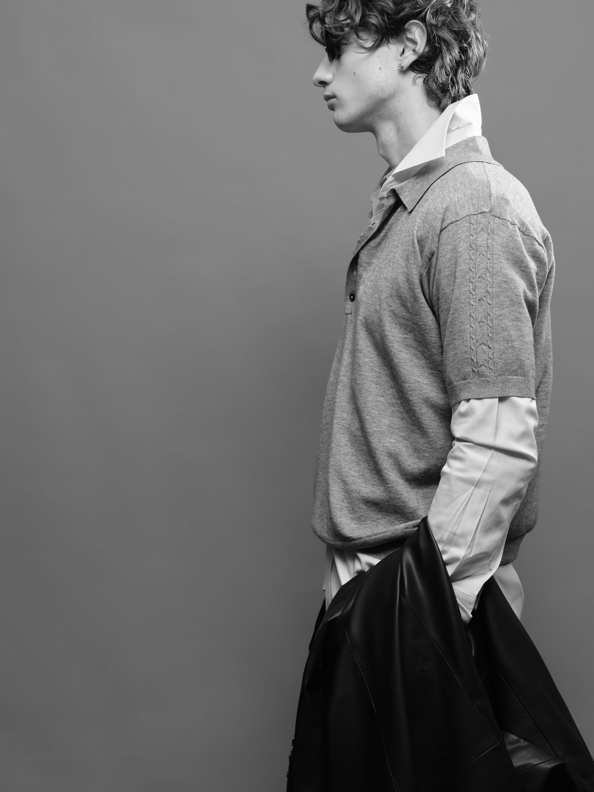 Stylish person in layered fashion with jacket. Monochrome side profile shot.