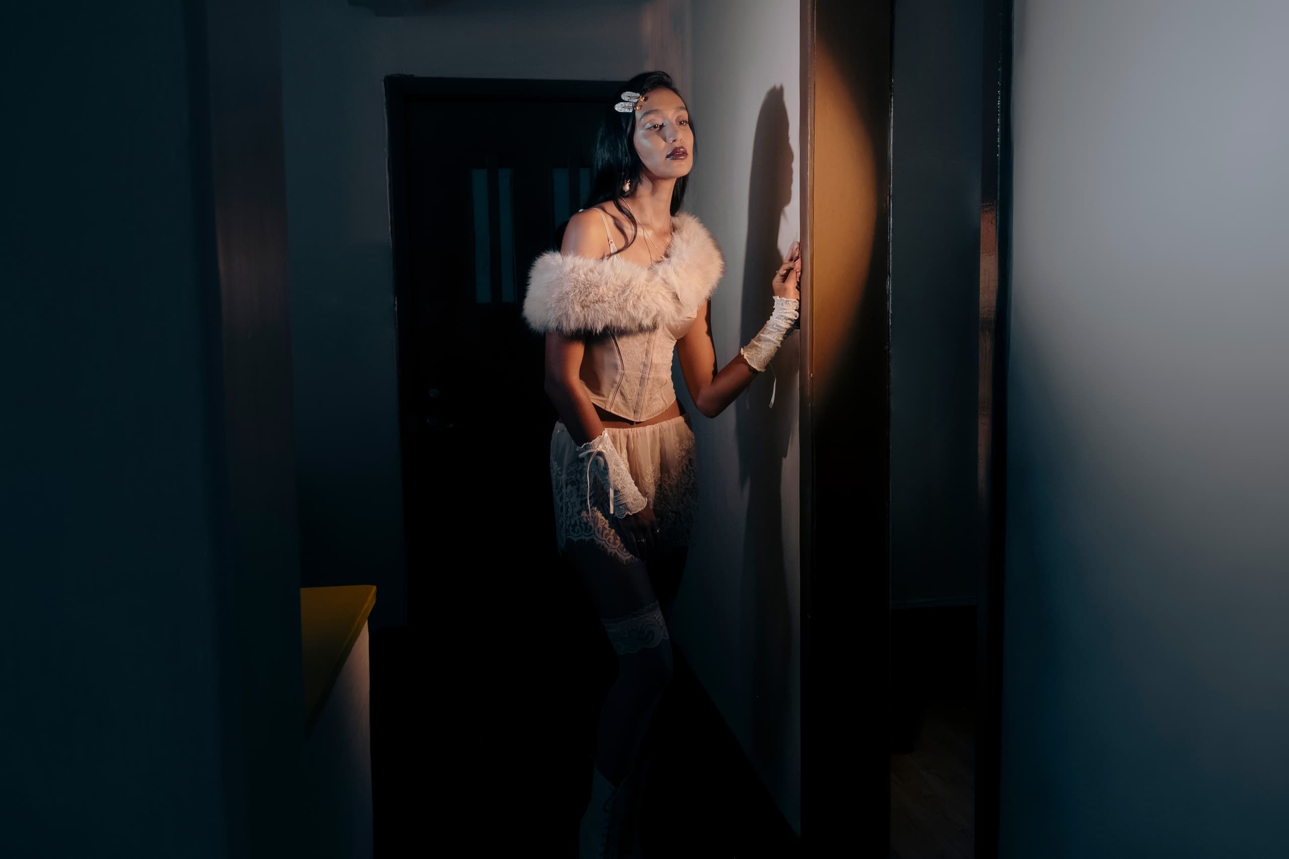 Woman in elegant vintage lingerie under dramatic lighting.