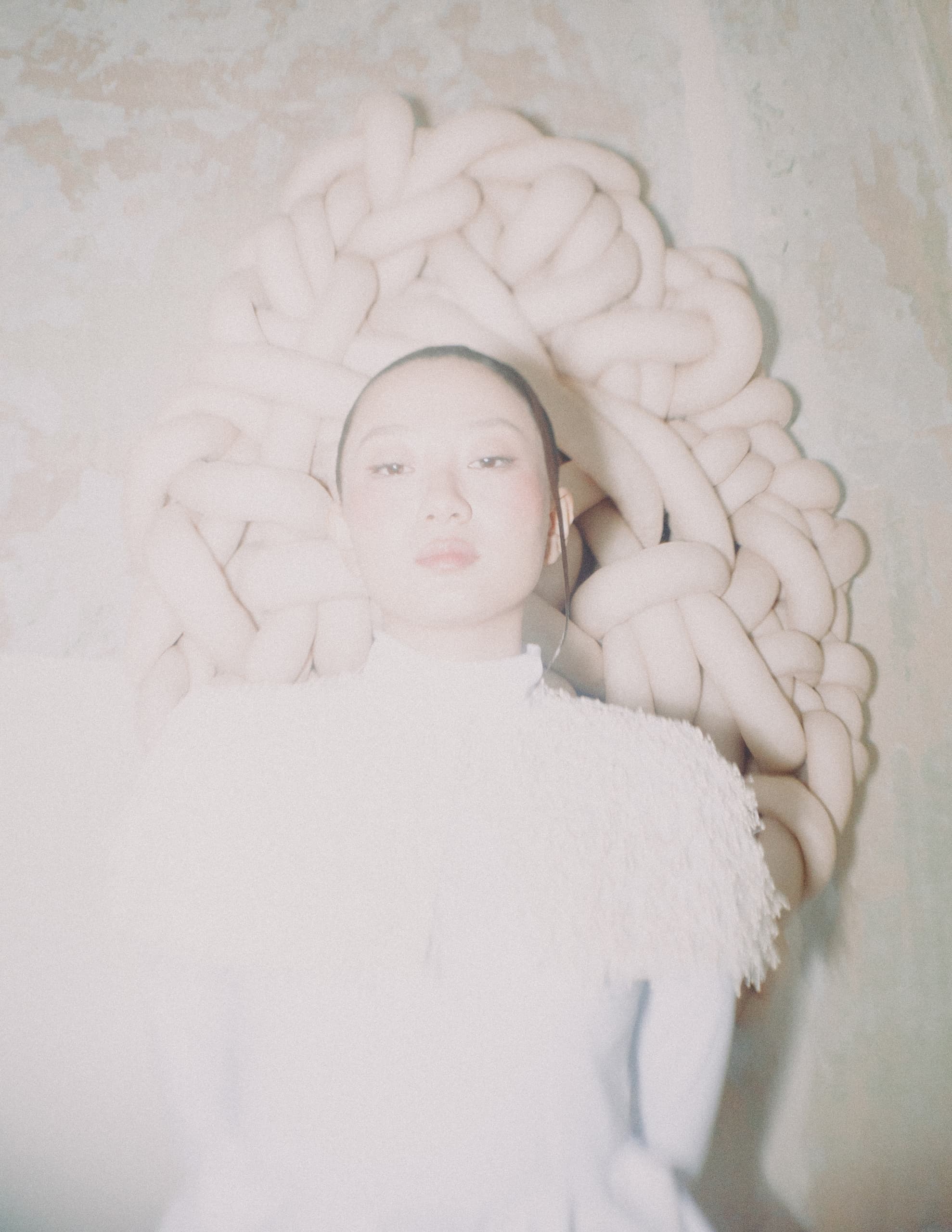 Avant-garde fashion with braided headpiece and textured white garment.