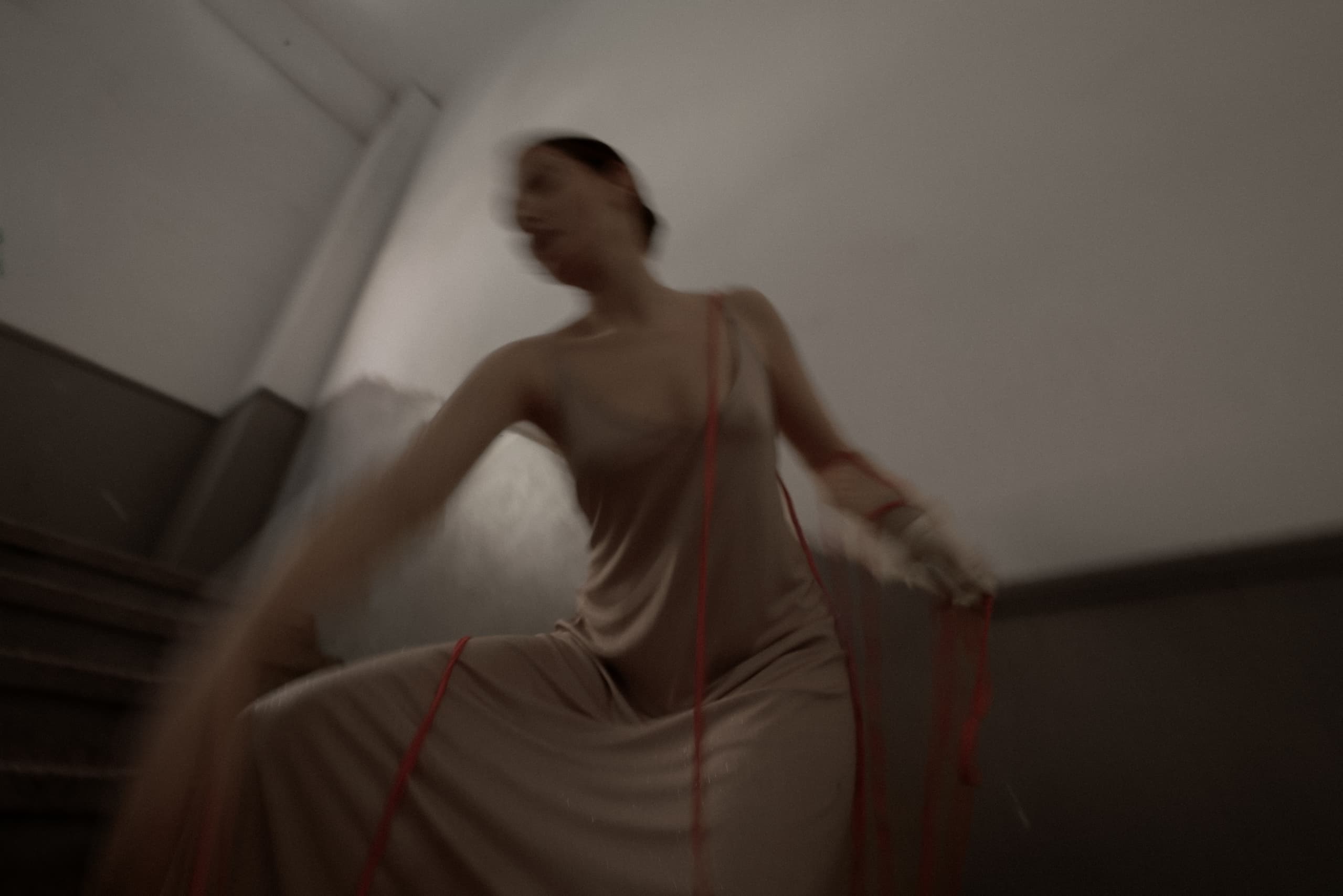 Blurry motion of woman with red threads, creating an abstract, artistic scene.