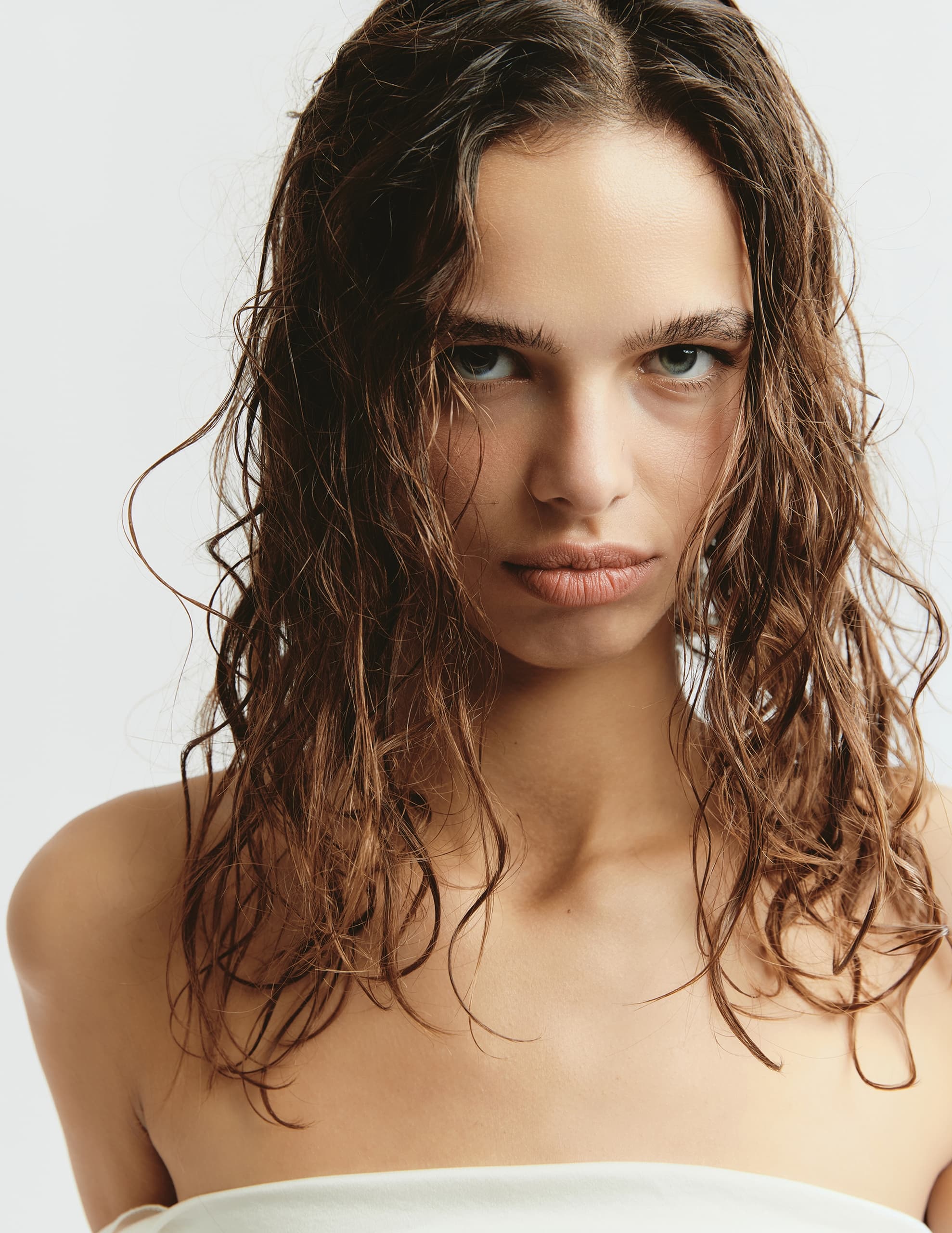 Woman with wet hair and bare shoulders gazing intensely at the camera.