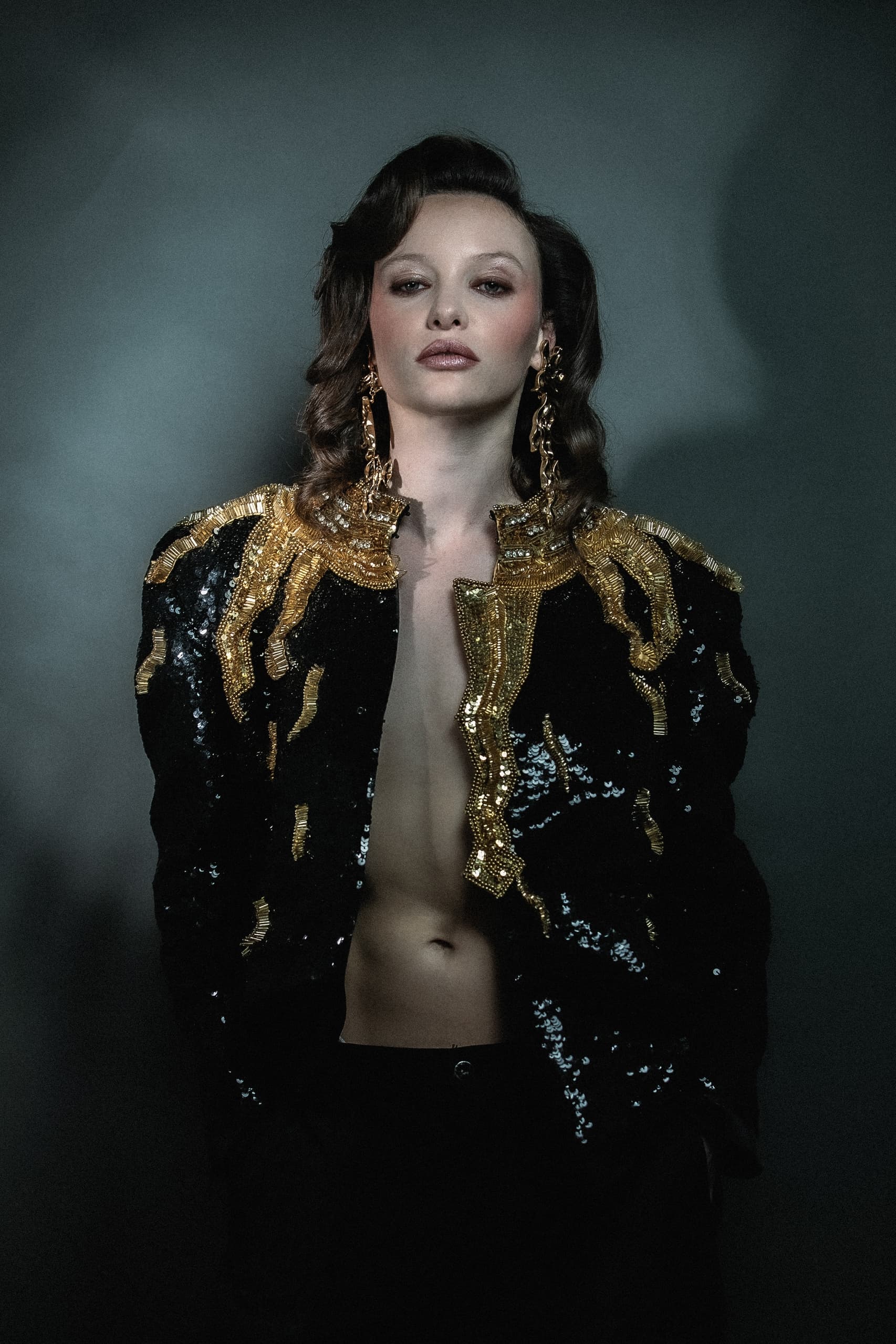 Elegant woman in black and gold sequin jacket with bold accessories. Fashion portrait.