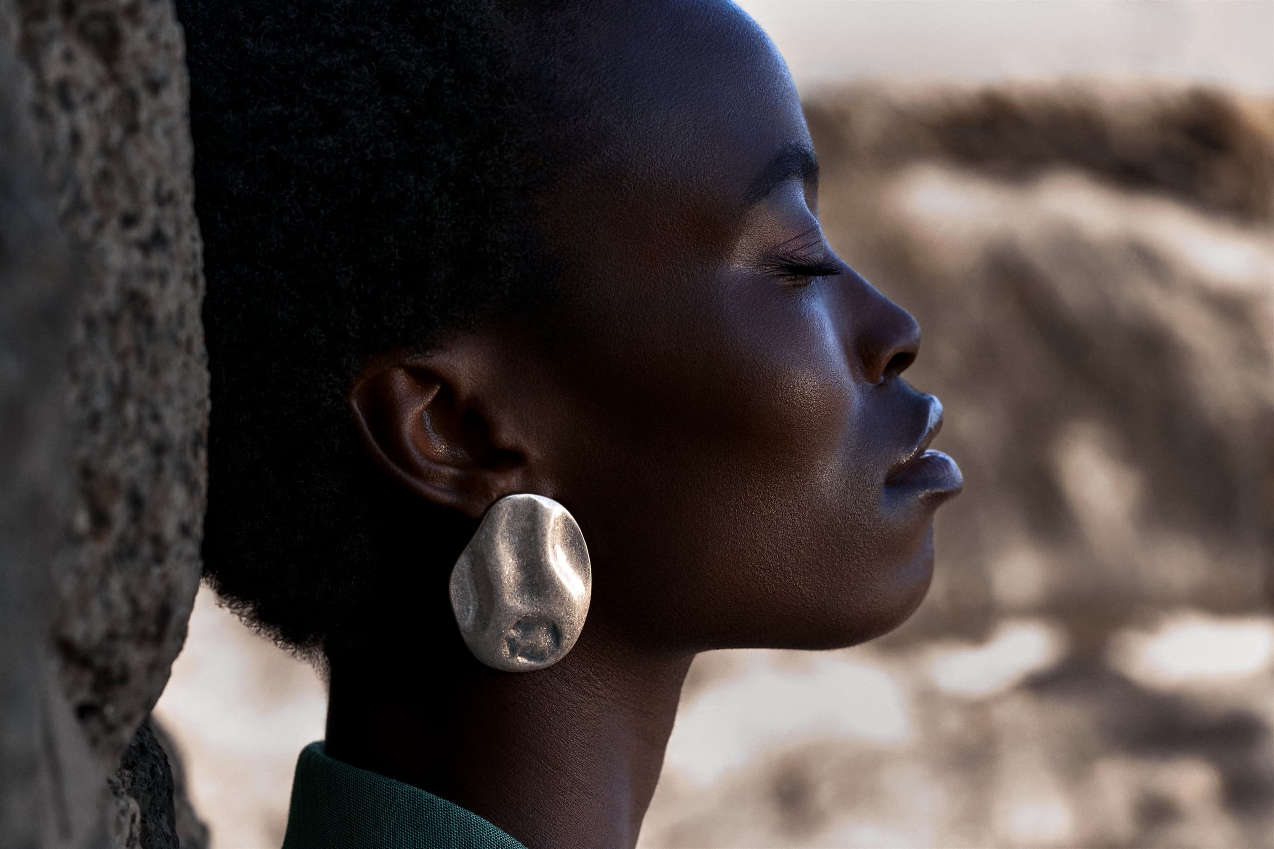 Profile of a woman with large silver earring, serene expression.