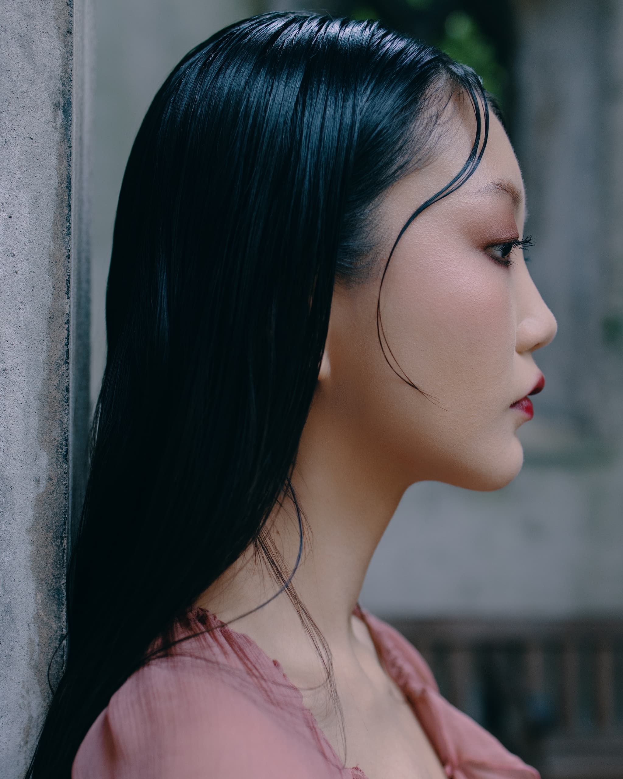 Side profile of a woman with sleek black hair and a serene expression.