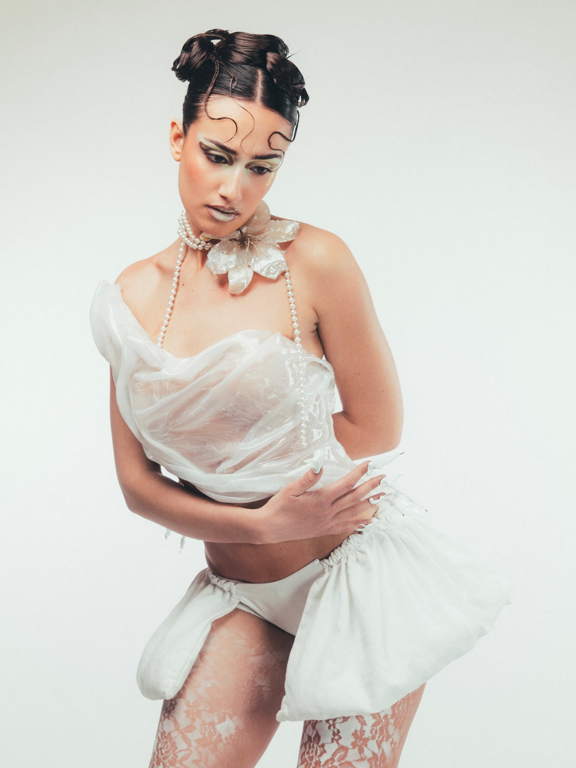 Avant-garde fashion model with unique hairstyle and white lace outfit.