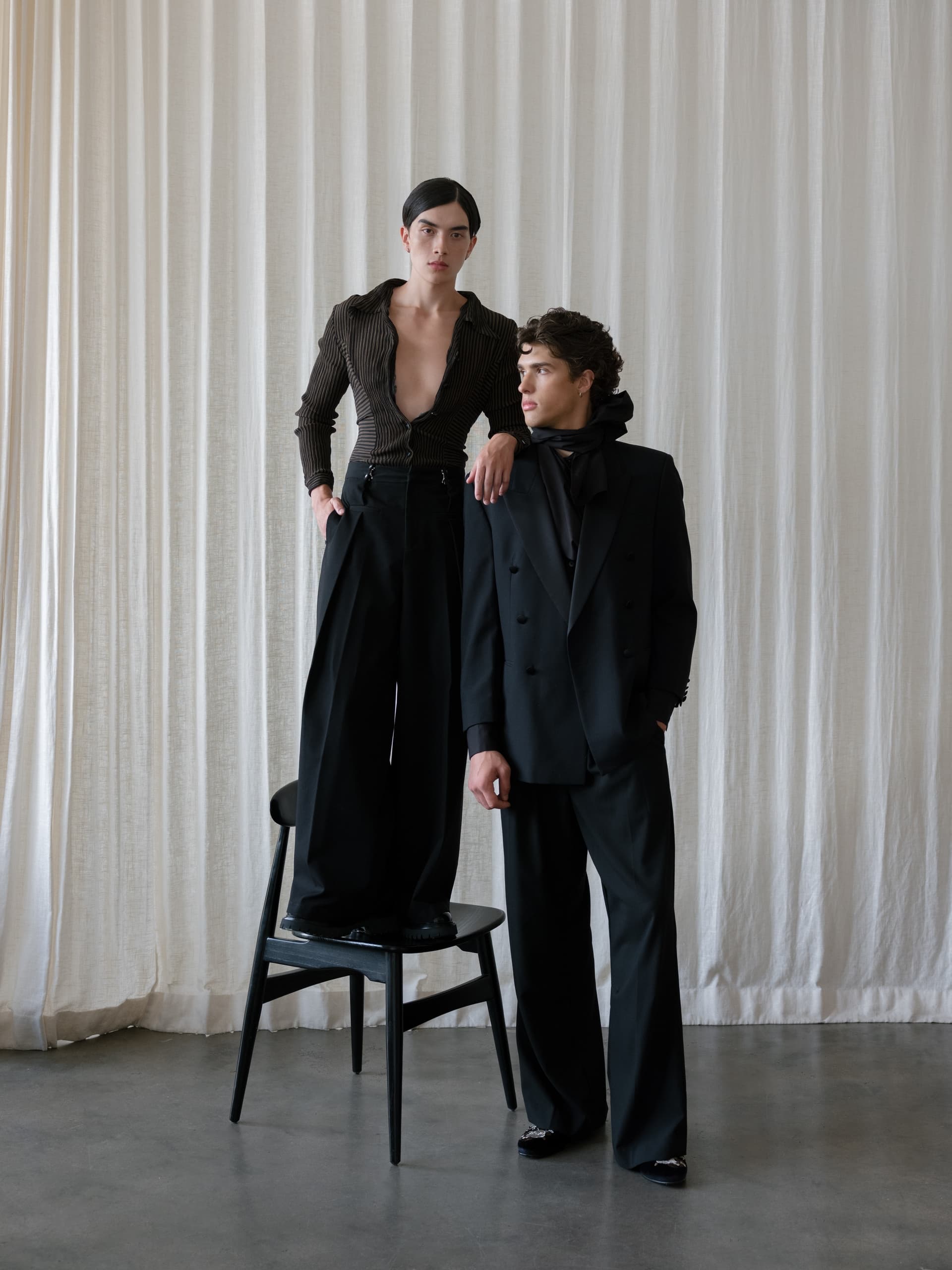 Fashionable models in black attire, styled in an elegant indoor setting.