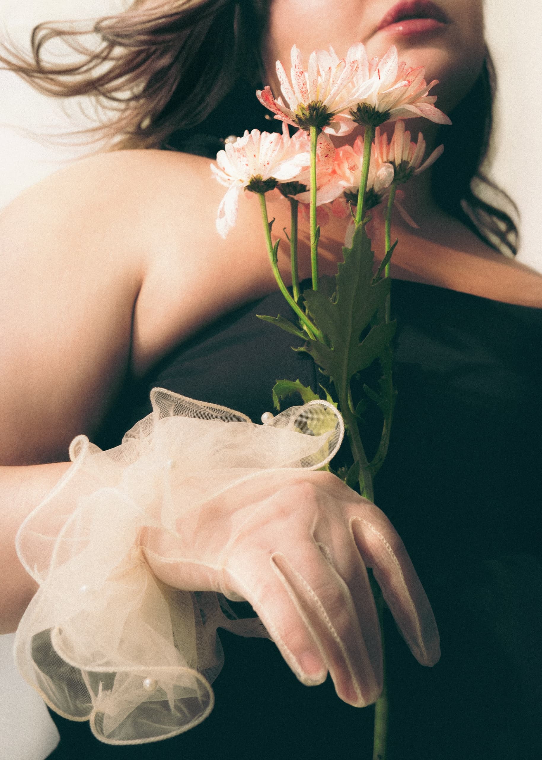 Elegant woman holding pink flowers with delicate gloves.