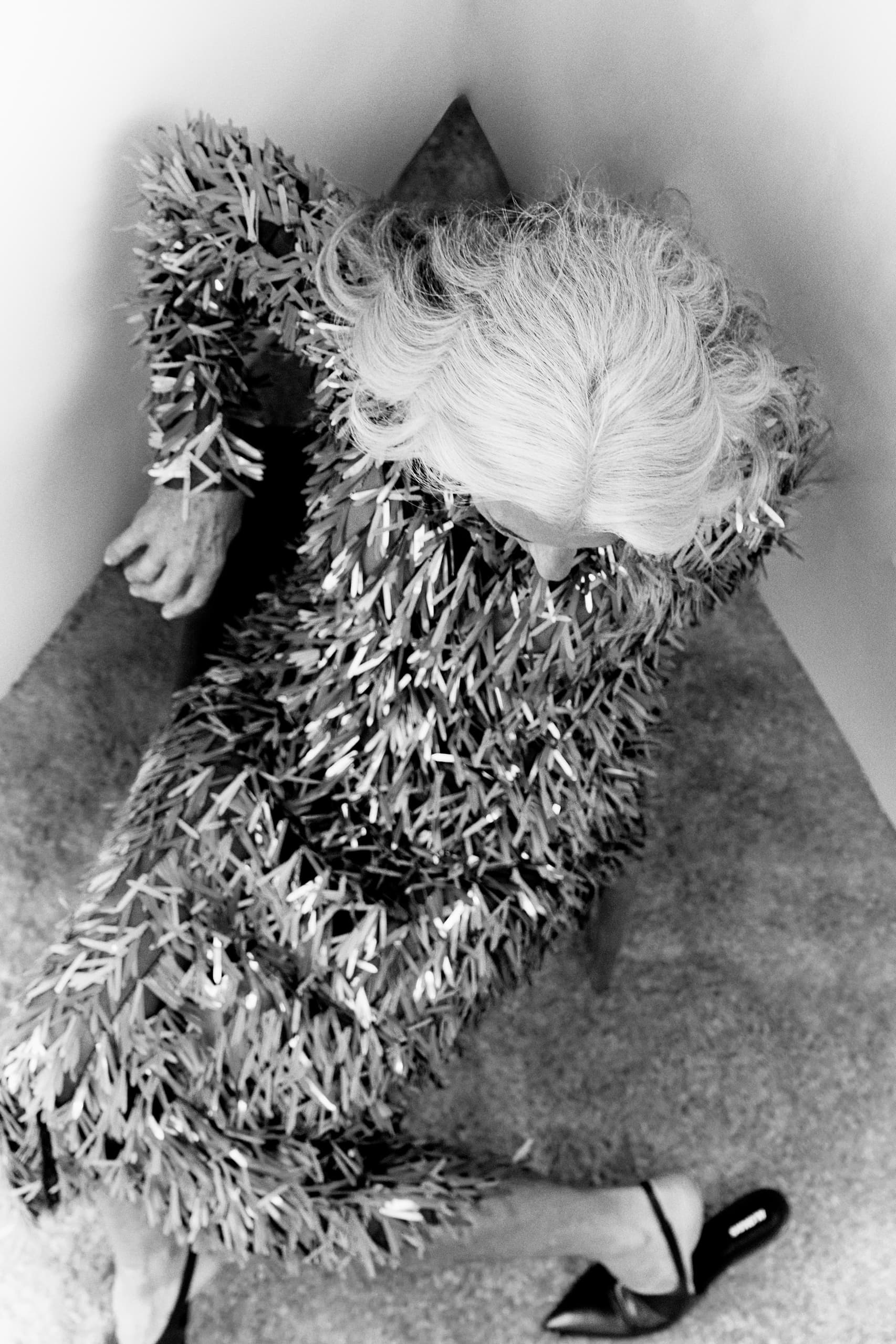 Monochrome fashion shot of a person in a textured dress sitting in a corner.