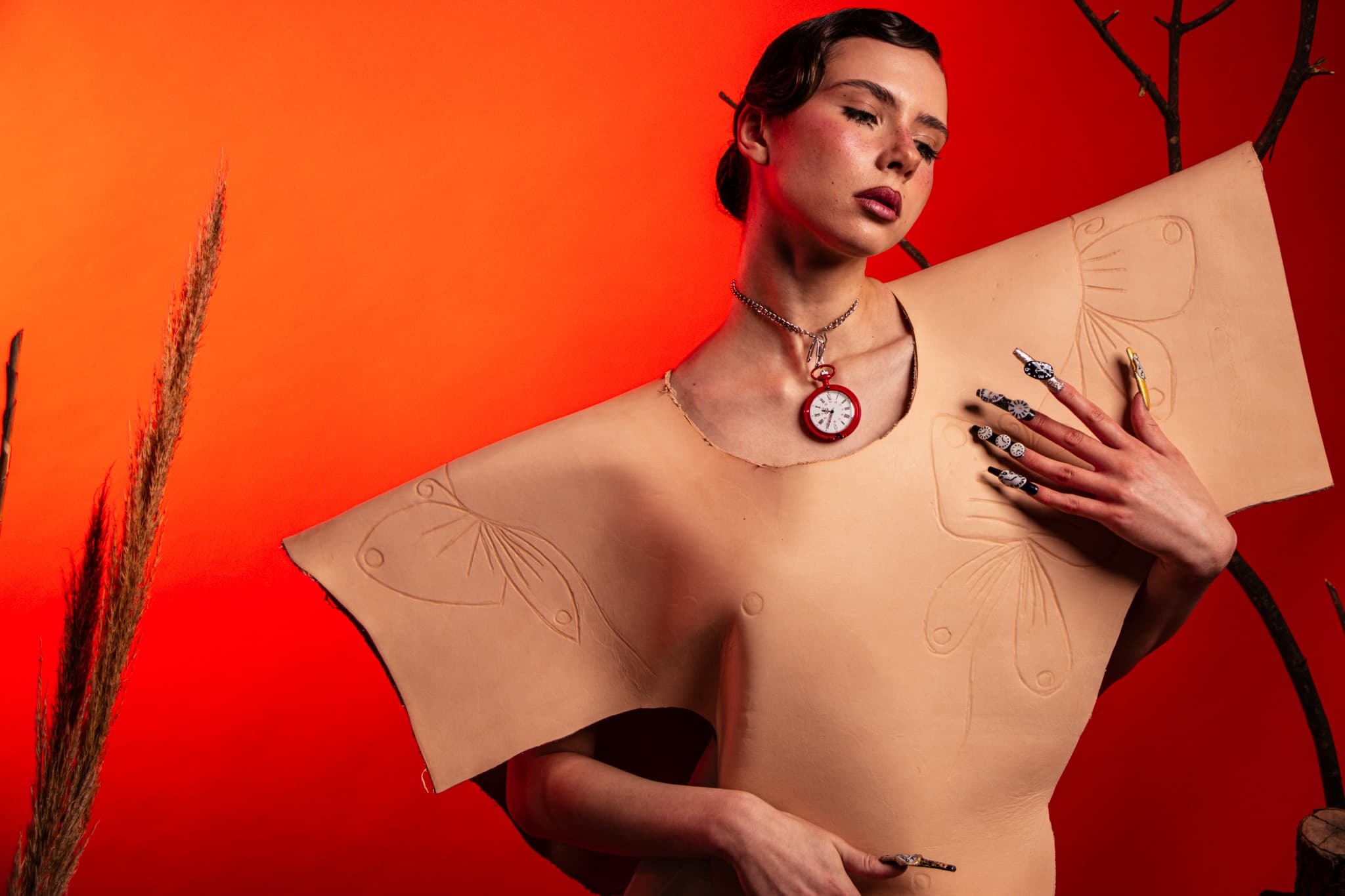 Fashion model in avant-garde outfit against vibrant orange background.