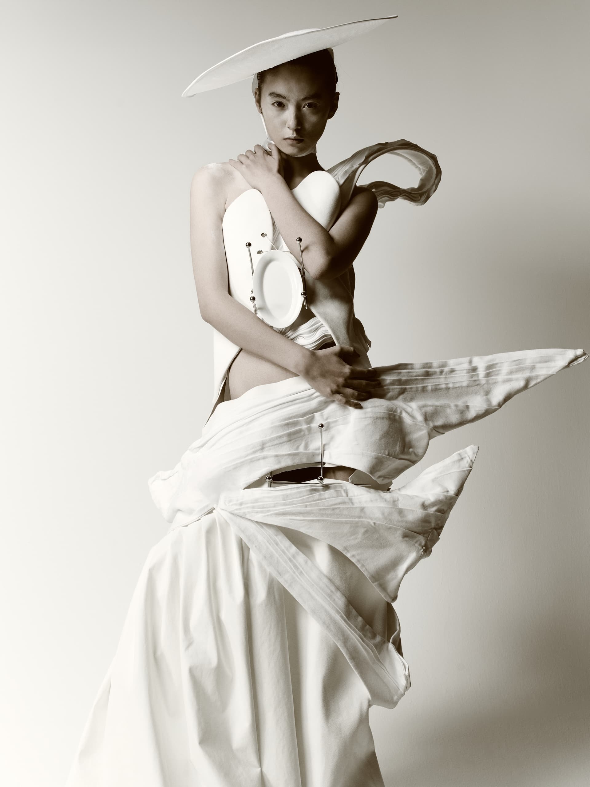 Avant-garde fashion model in sculptural white dress, artistic photography.