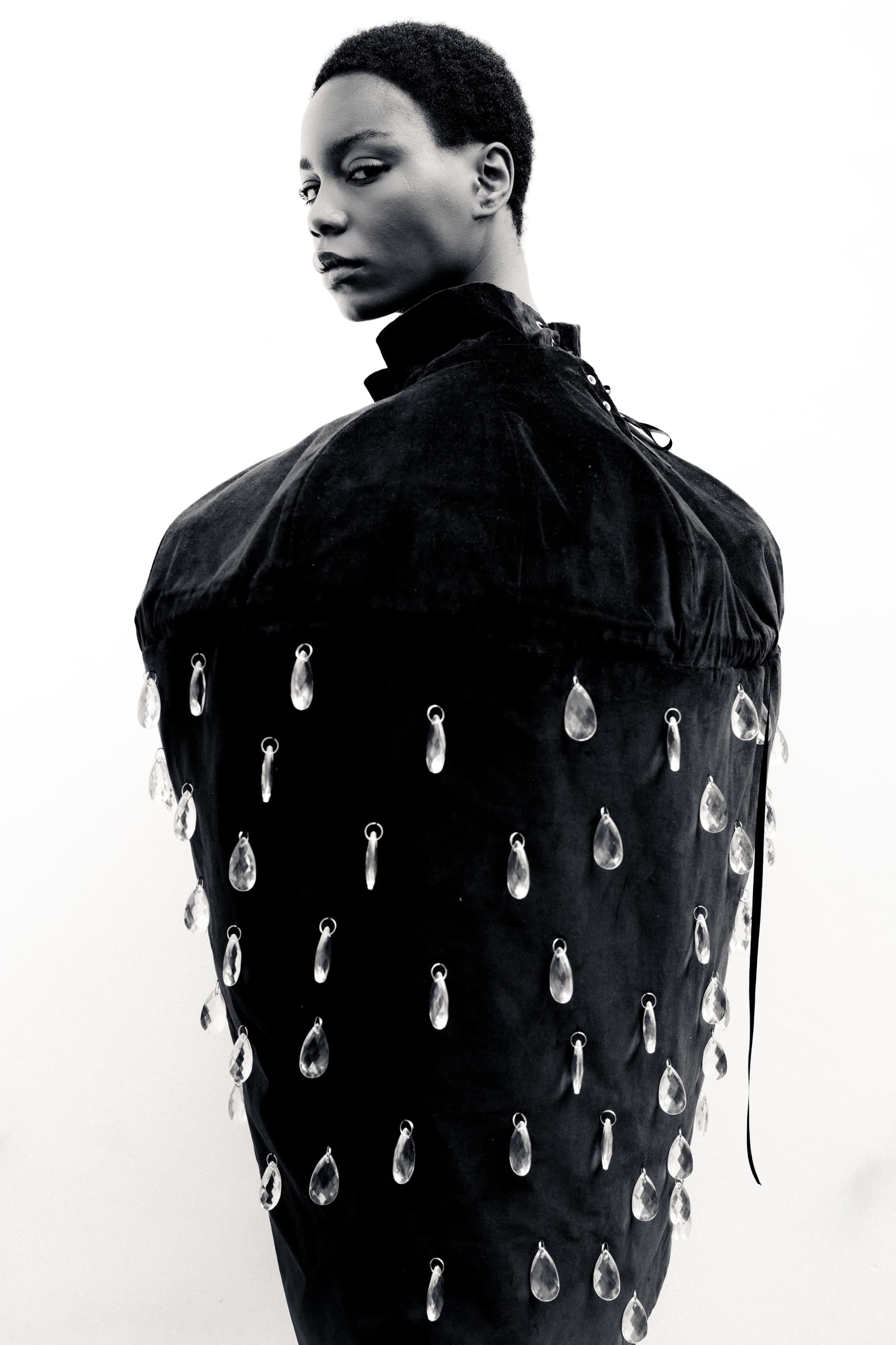 Fashion model in avant-garde black outfit with crystal embellishments.