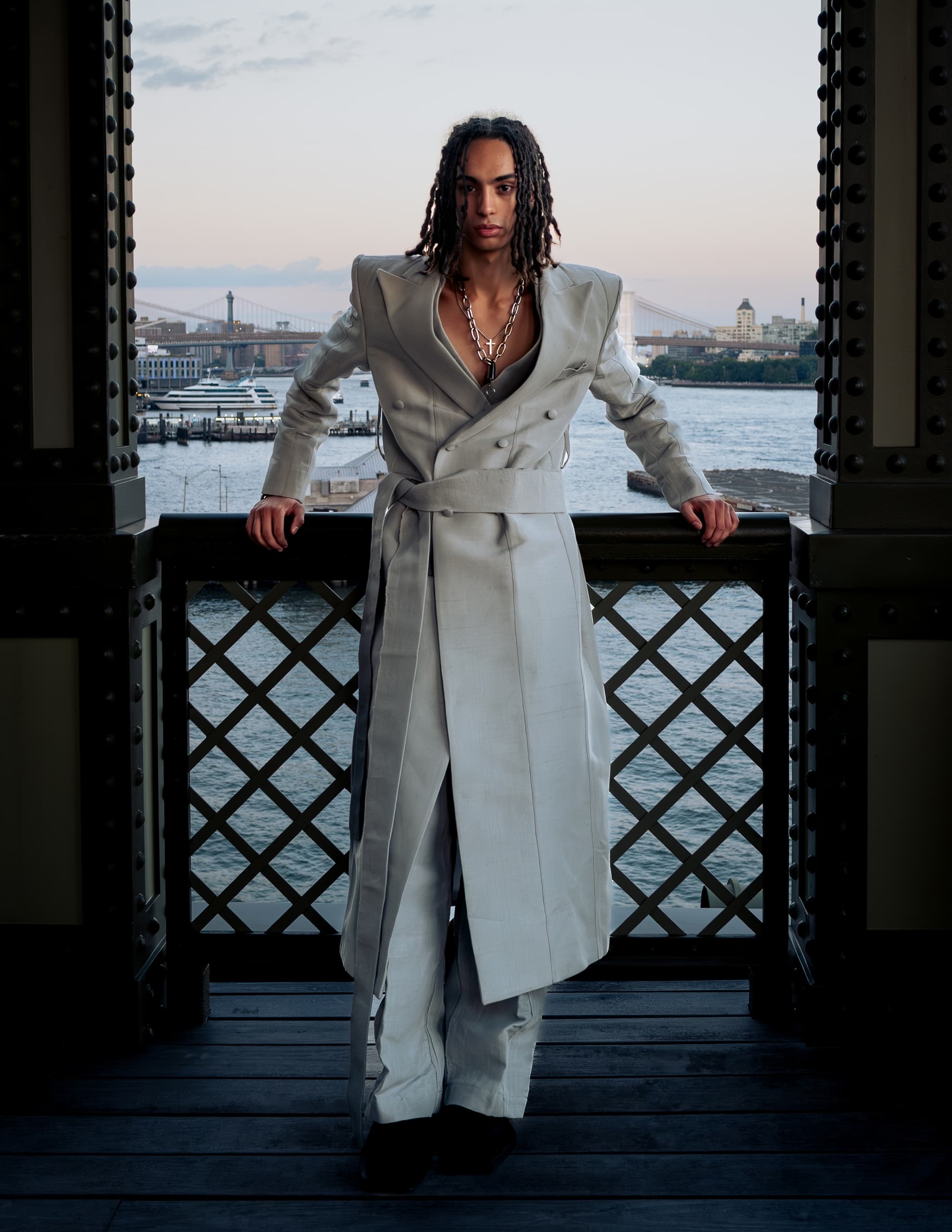 Stylish model poses in a unique gray suit by the waterfront.