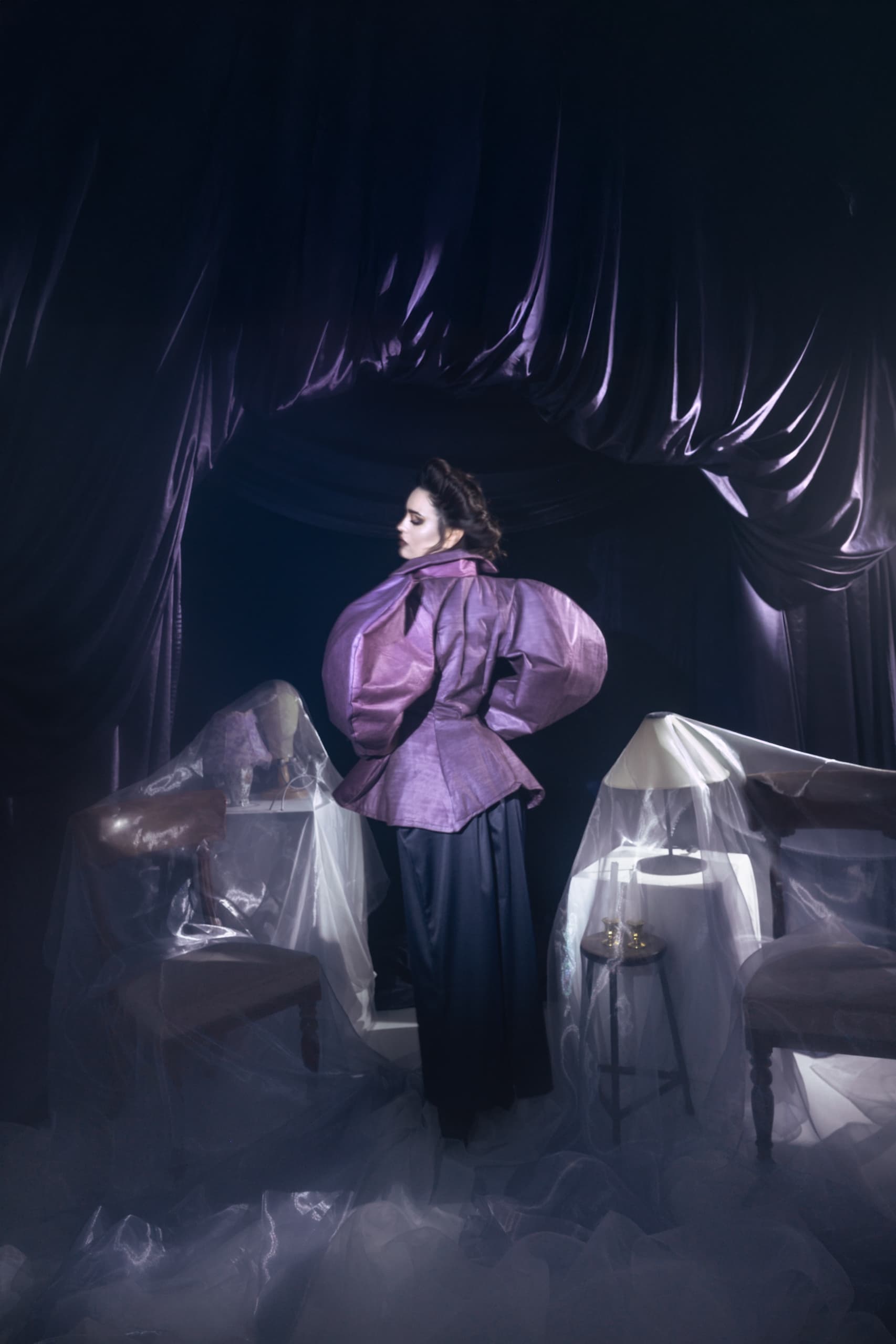Elegant woman in purple couture fashion, dramatic setting.