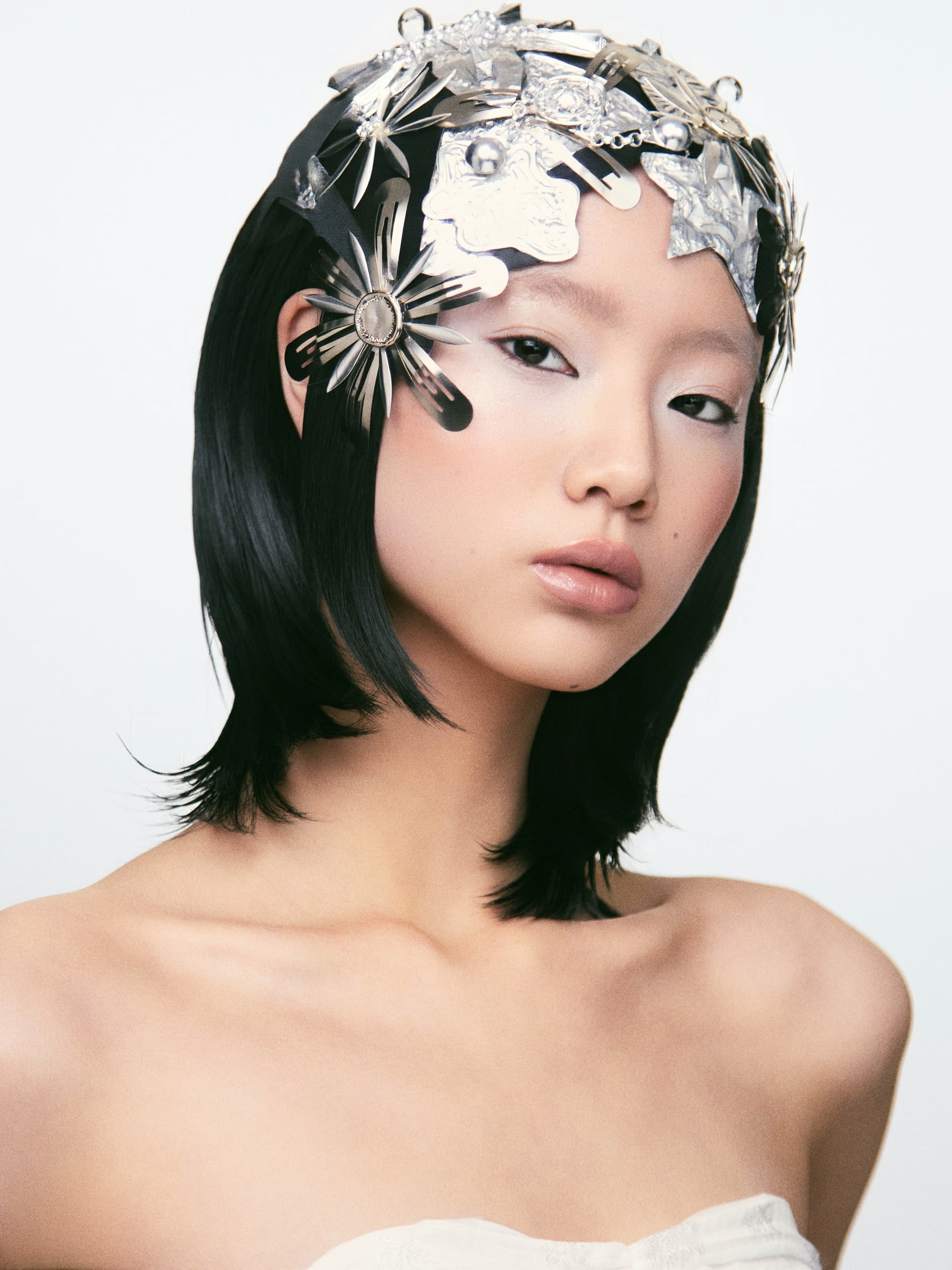 Fashion model wearing a unique metallic headpiece, showcasing innovative design.