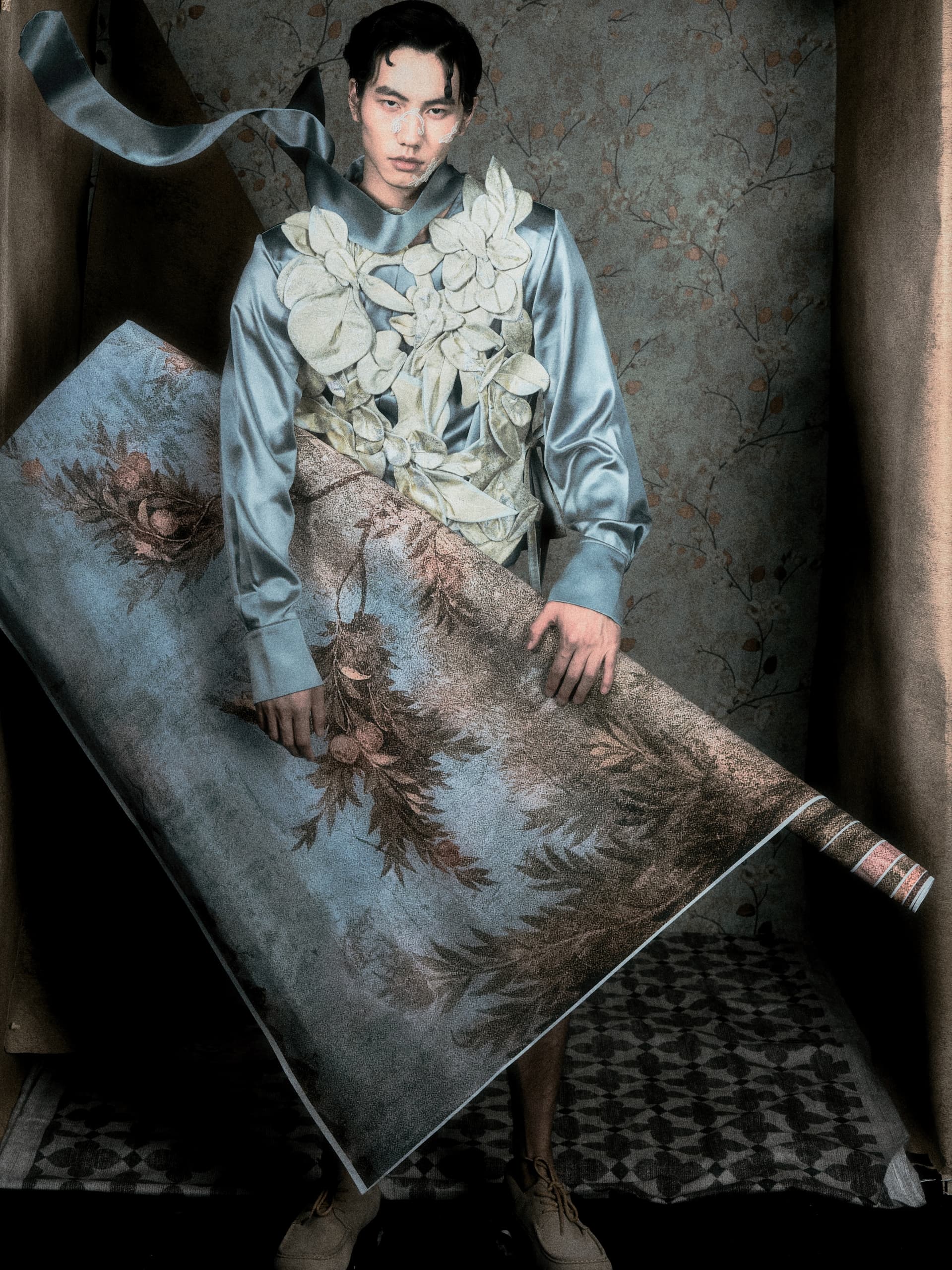 Fashion model with floral outfit holding a rolled decorative wallpaper.