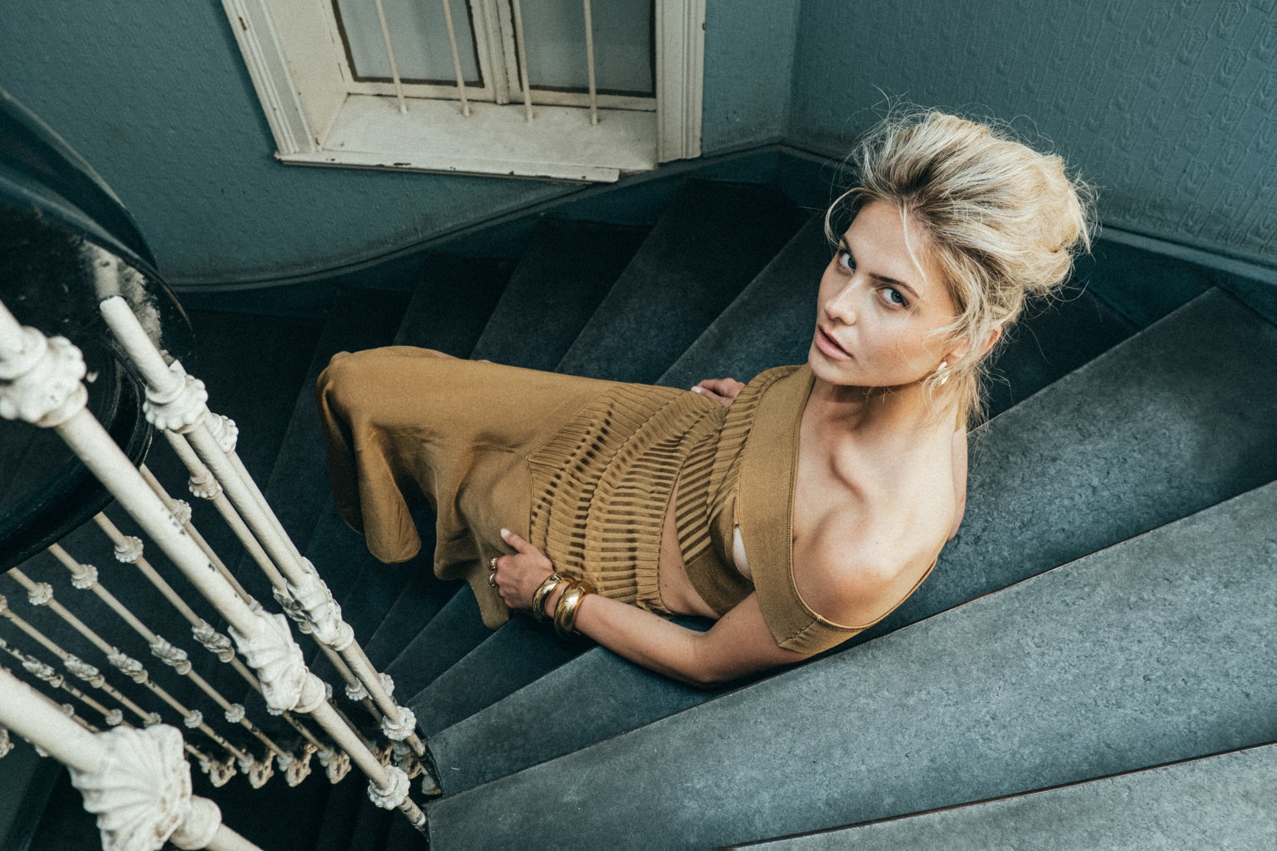 Woman in elegant outfit ascending a spiral staircase, top view. Fashion photography.