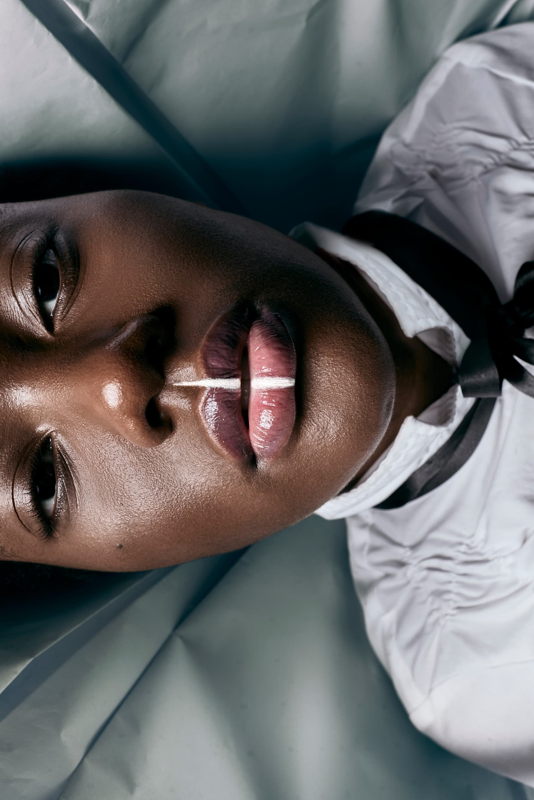 Close-up portrait of a person with glossy lips and white shirt detail.