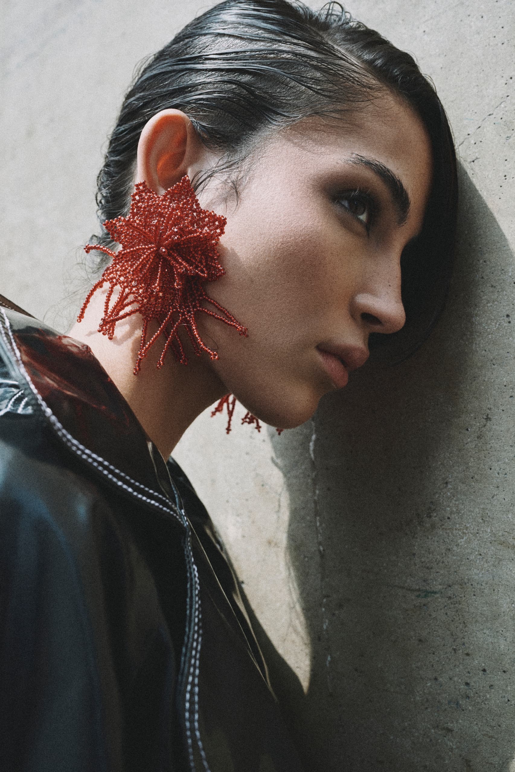 Model with red beaded earring and slicked hairstyle.