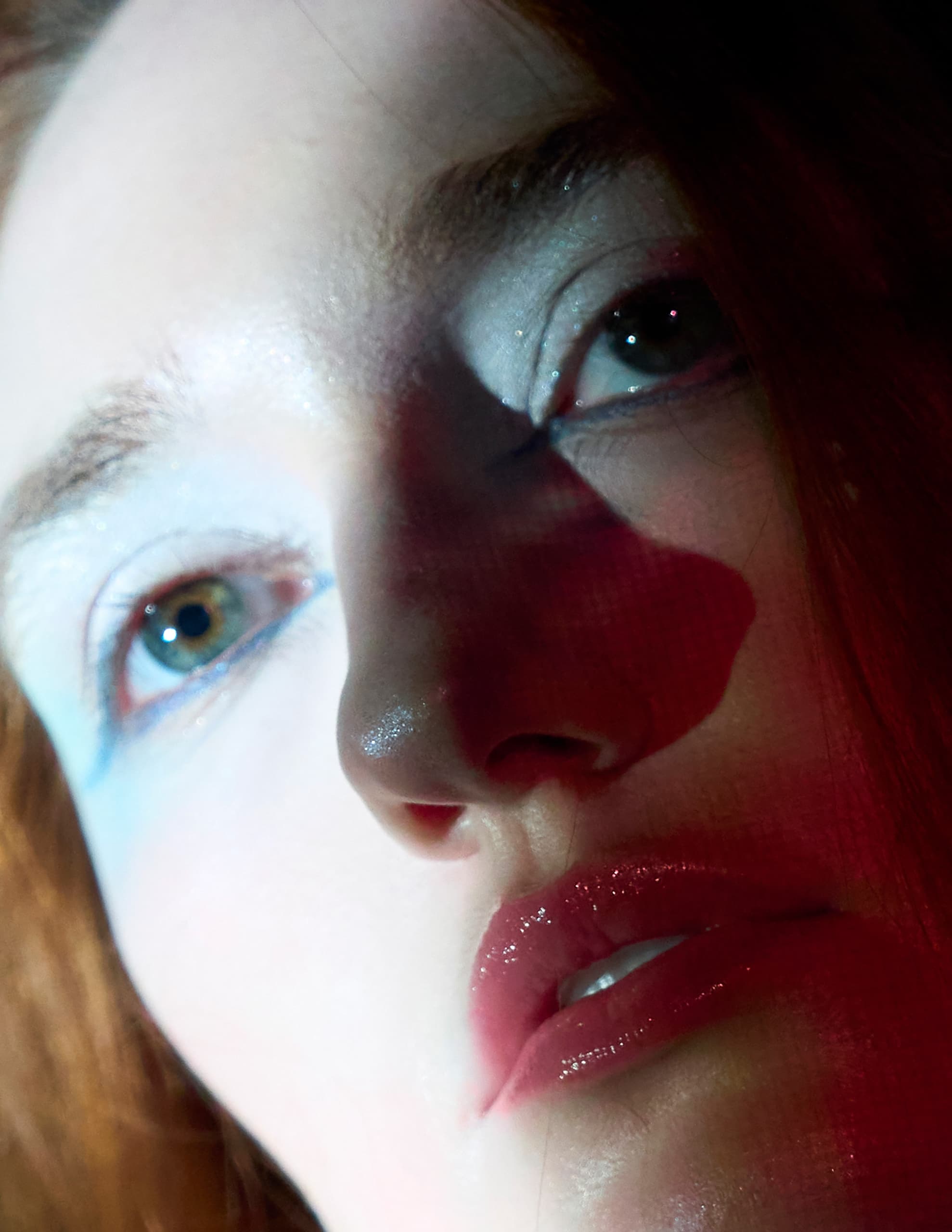 Artistic portrait with unique makeup and dramatic red lighting.