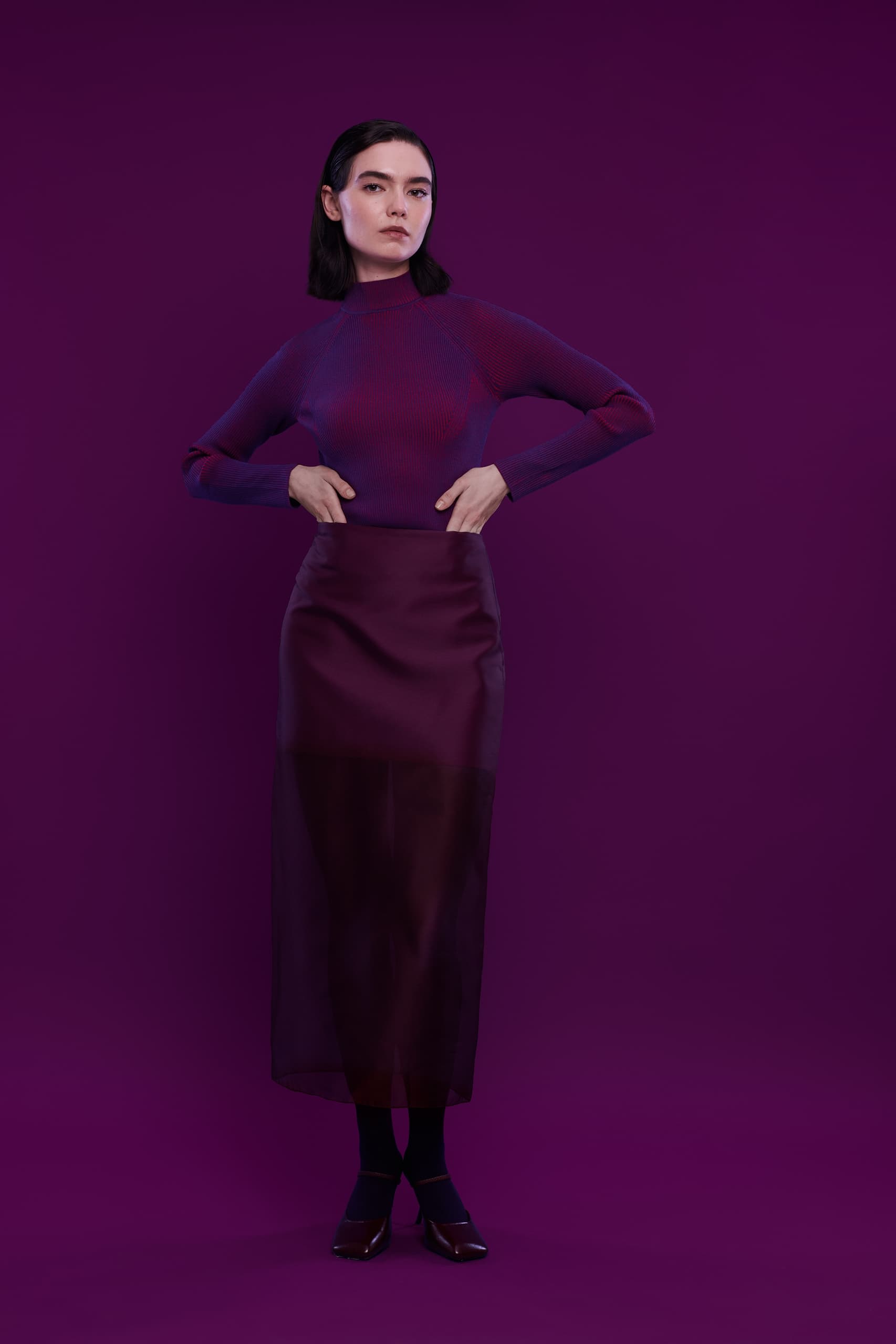 Woman in a purple outfit on matching purple background.