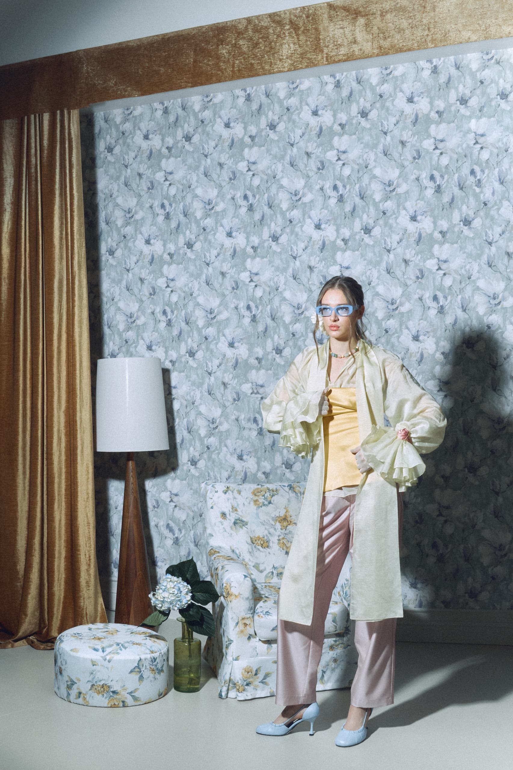 Vintage-inspired fashion in a floral room with elegant pastel outfit.