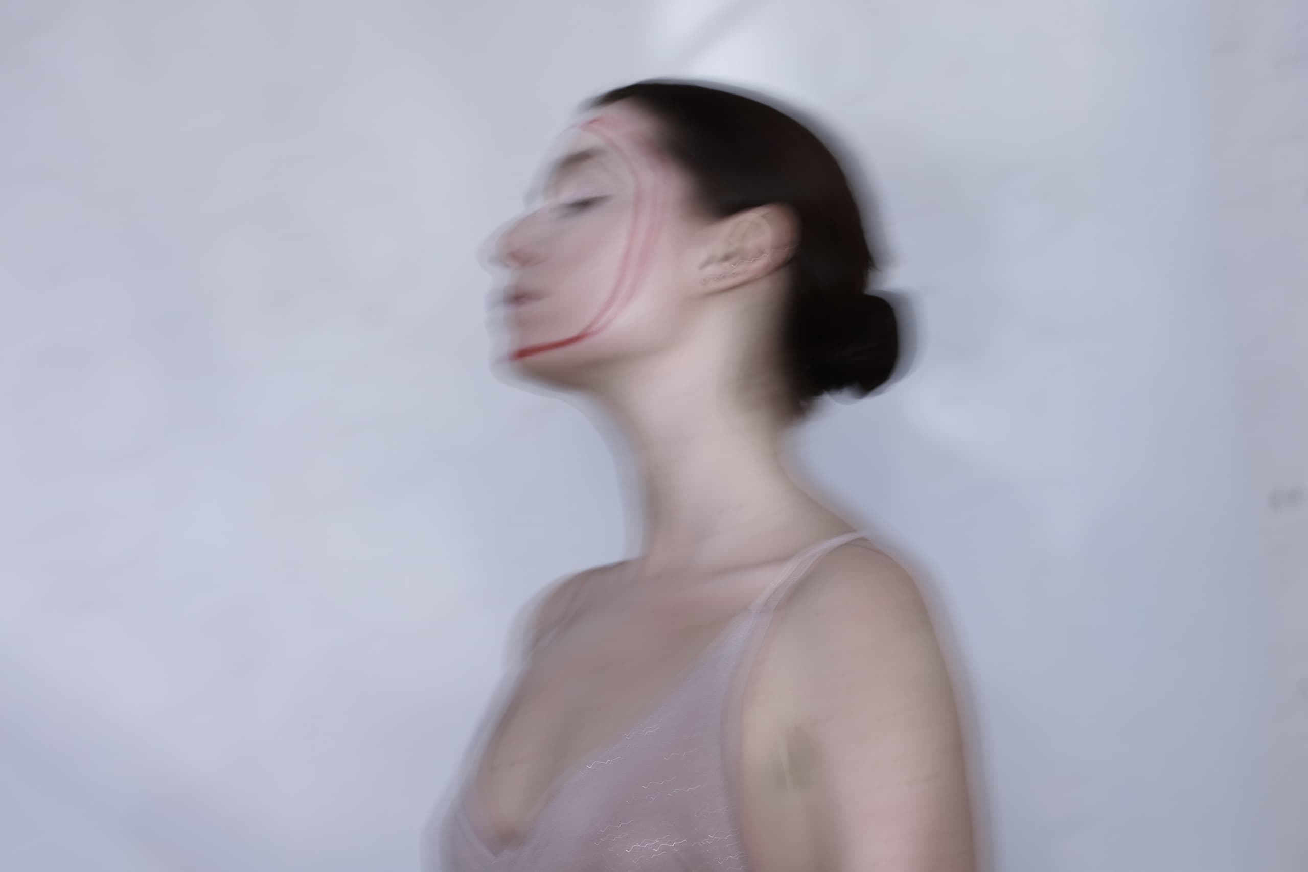Artistic blurred image of a woman with red face paint on a soft background.