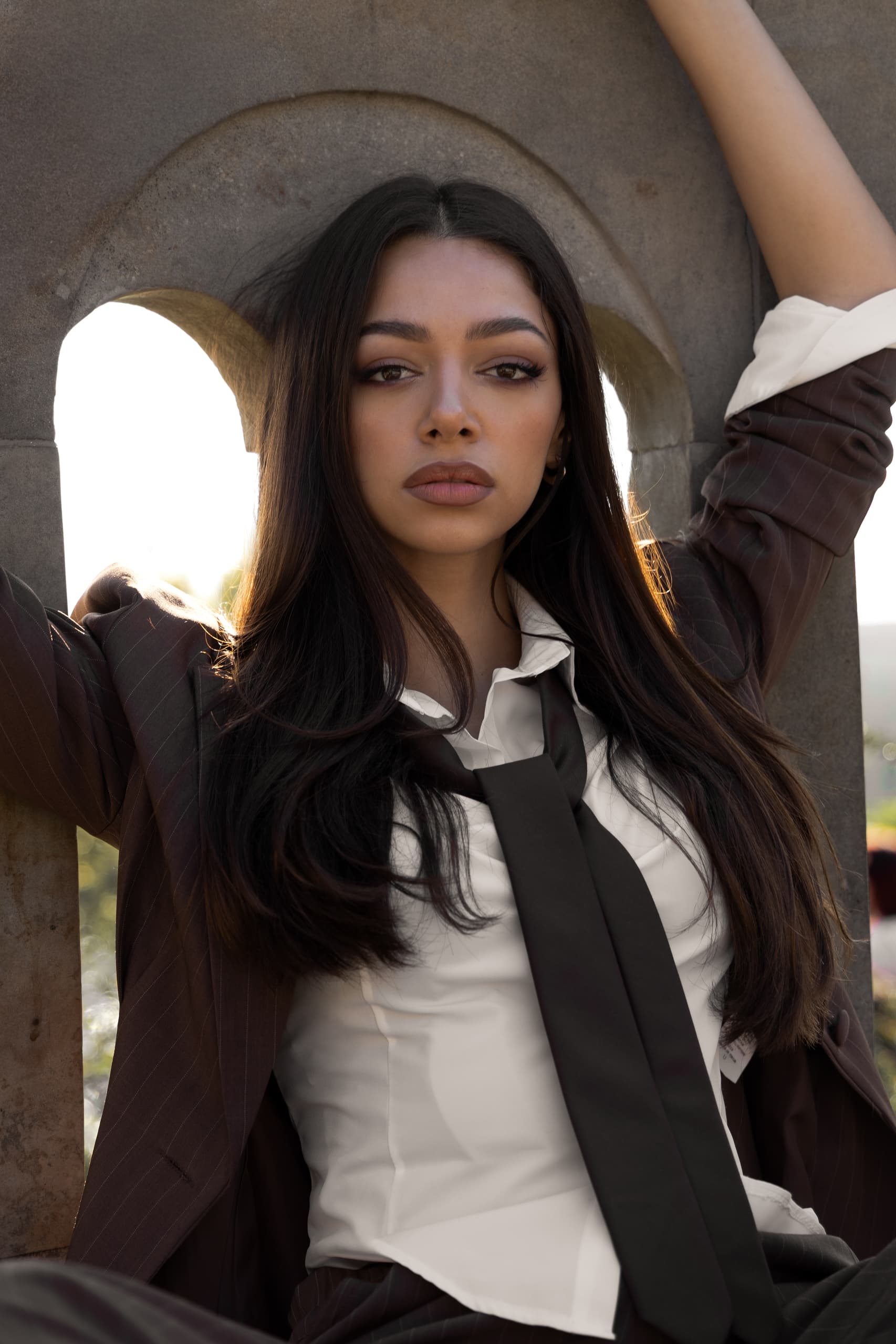 Woman in business attire posing confidently under an archway.