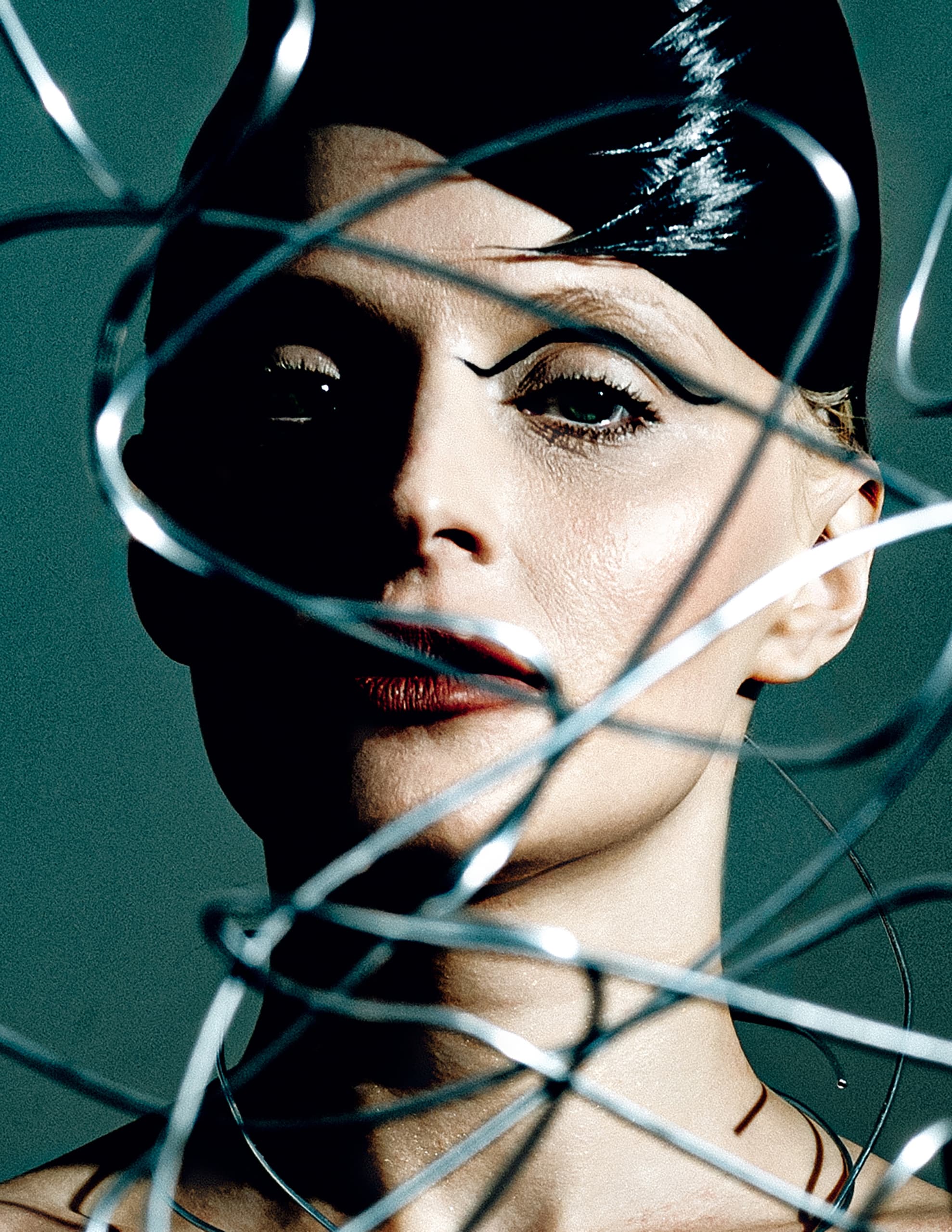 Avant-garde fashion portrait with wire overlay and dramatic makeup.