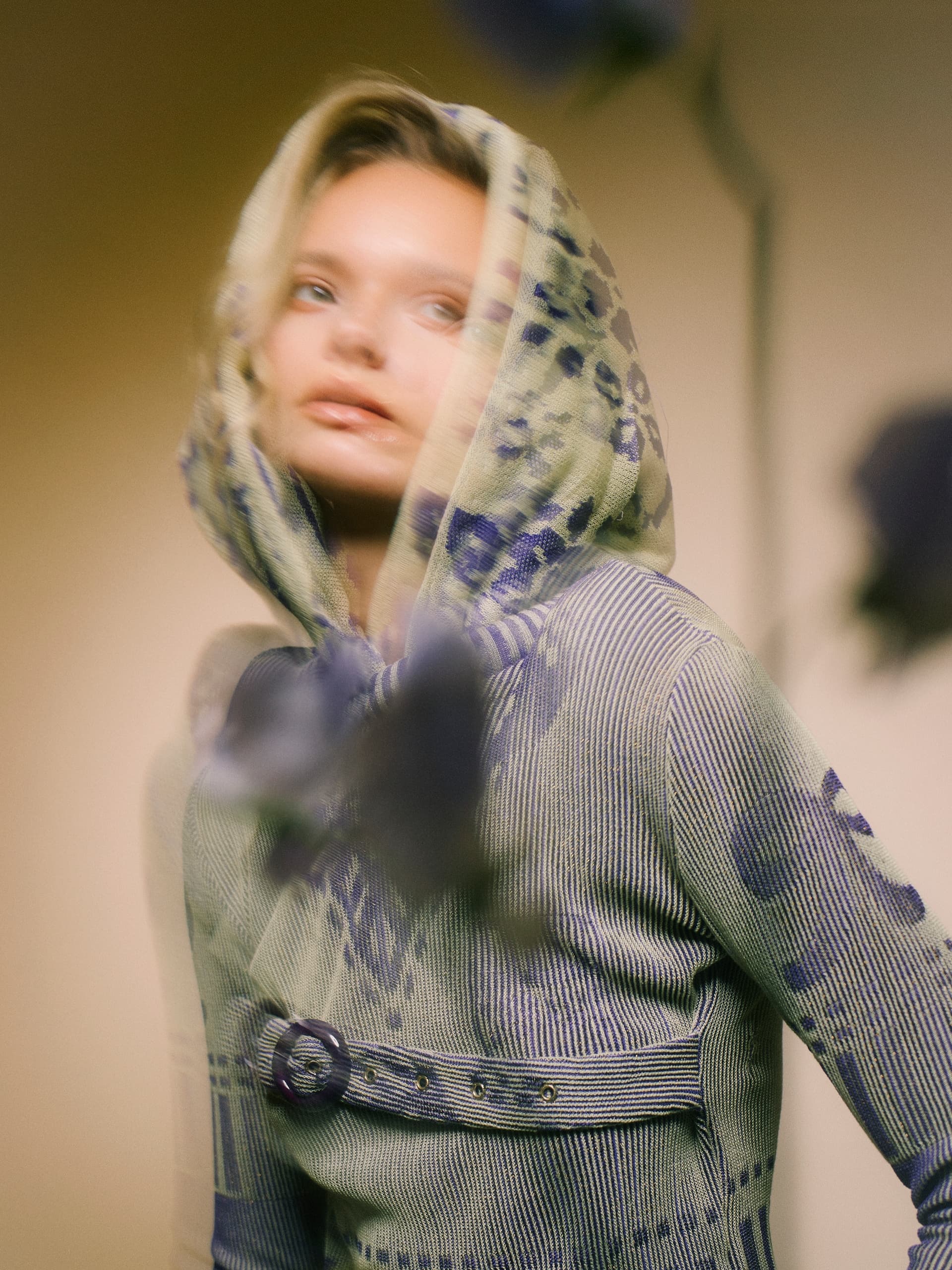 Blurry woman in a patterned hooded outfit, captured with soft focus.