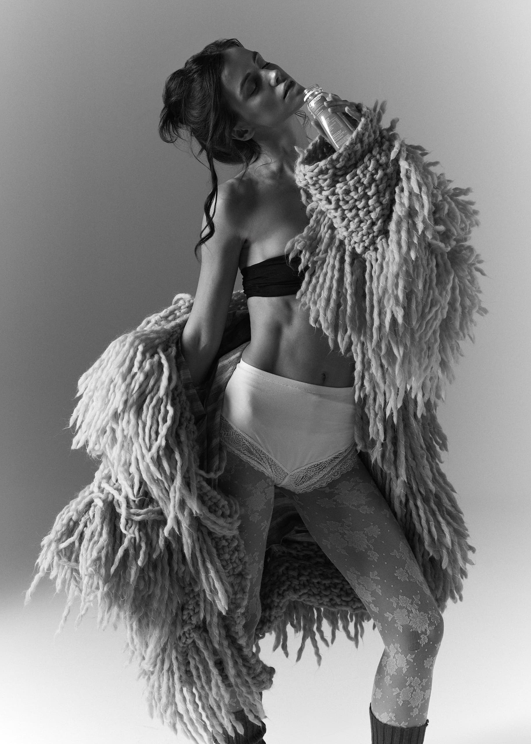 Fashion model in dramatic knitwear, vintage-inspired black and white photo.