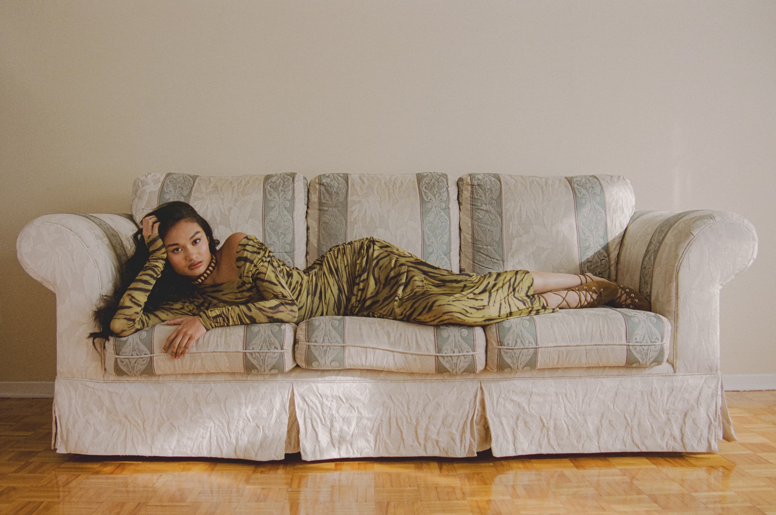 Woman in tiger-print dress laying on a patterned sofa in a minimalist room.