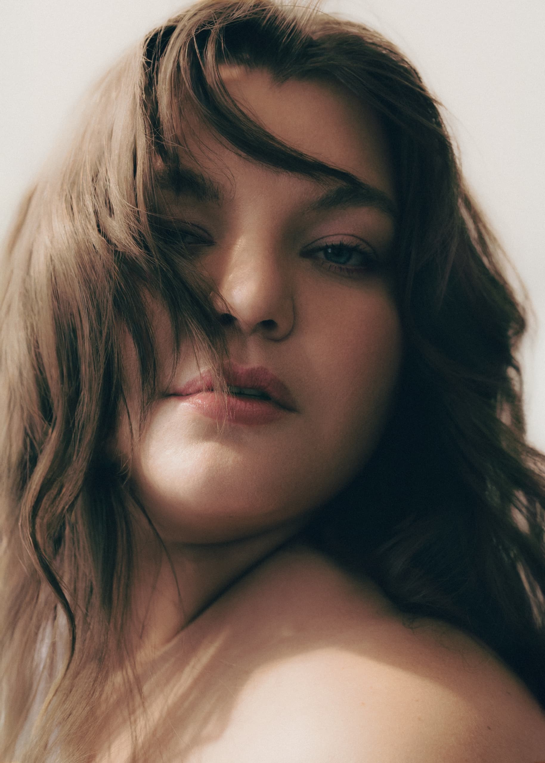 Portrait of a woman with wavy brown hair and soft natural lighting.