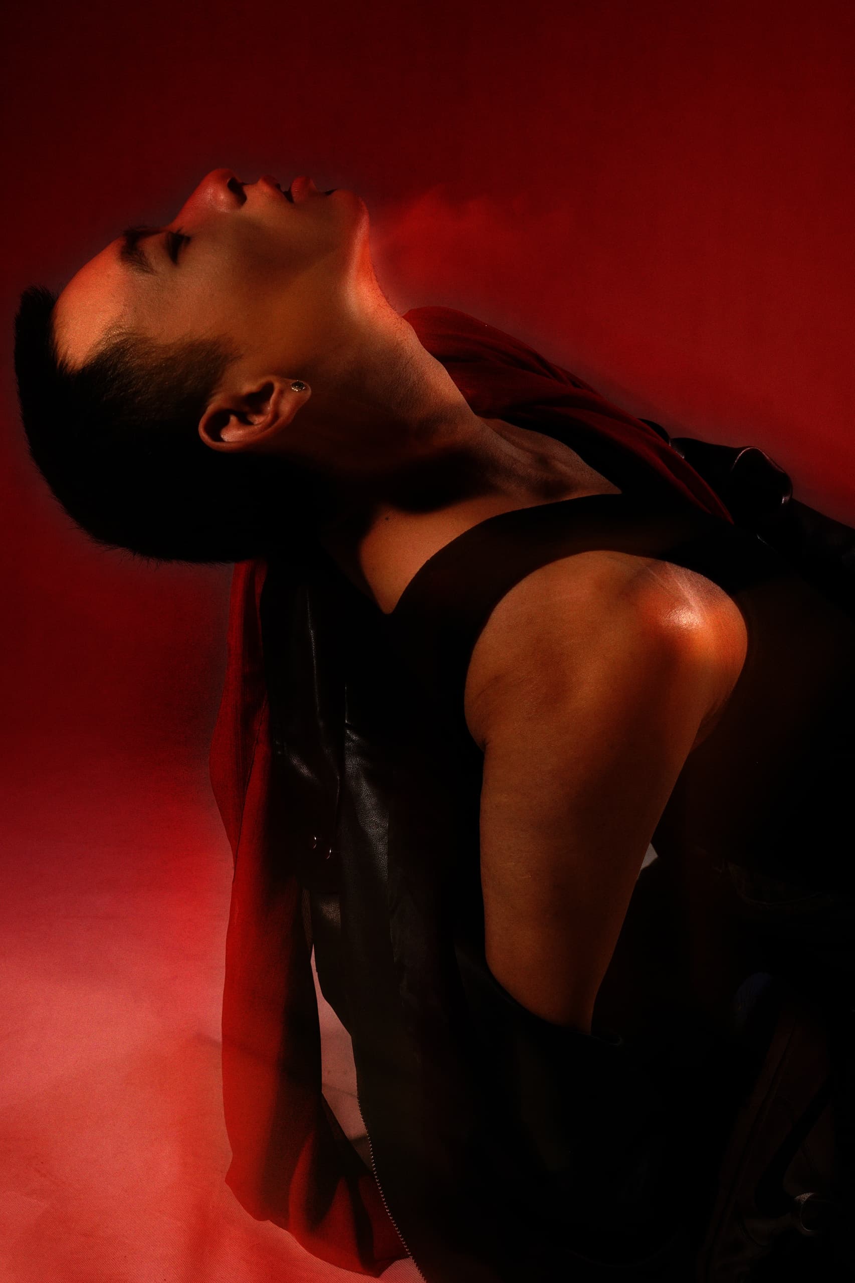 Person posing dramatically in red and black lighting.