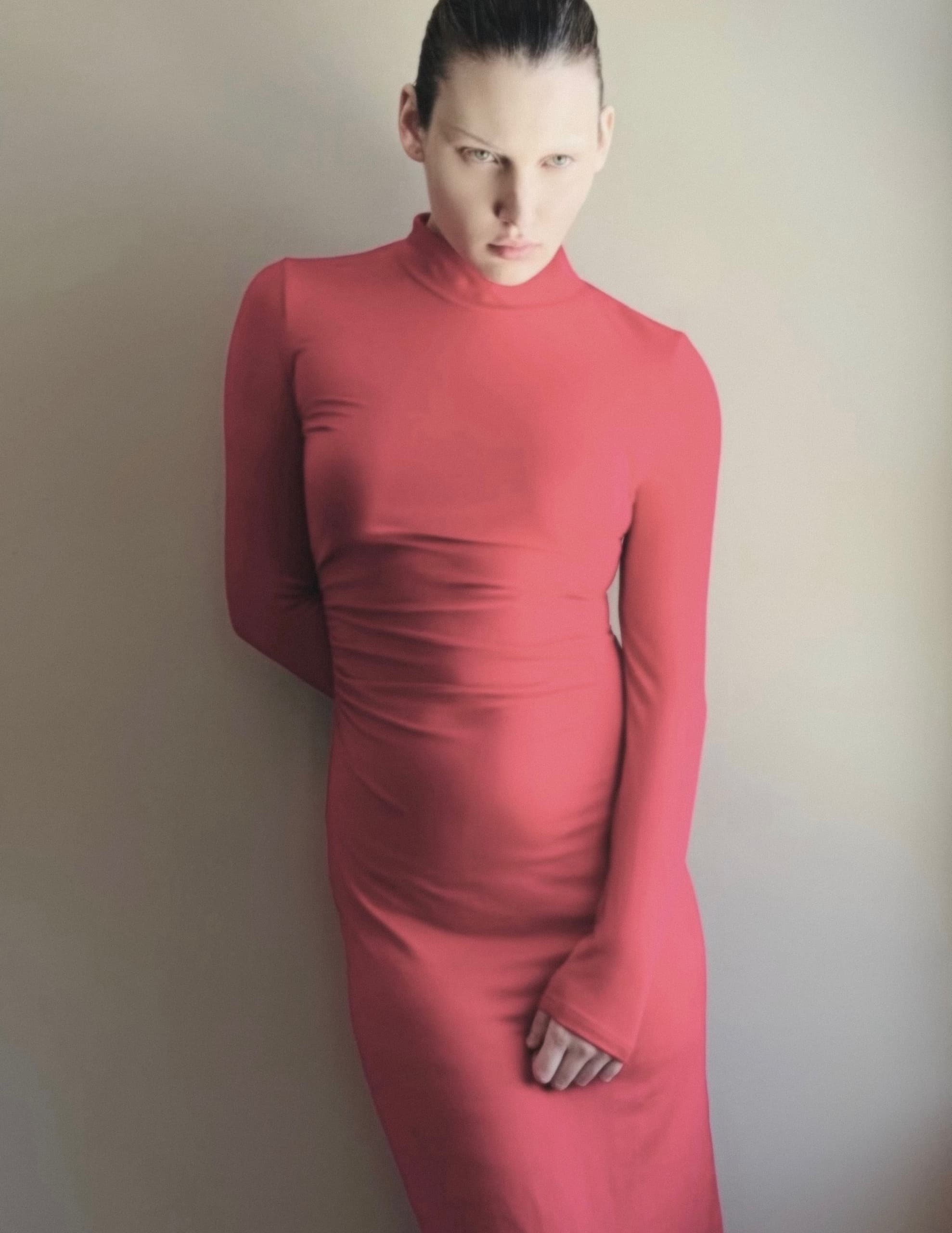 Person in a sleek red dress poses confidently against a neutral background.