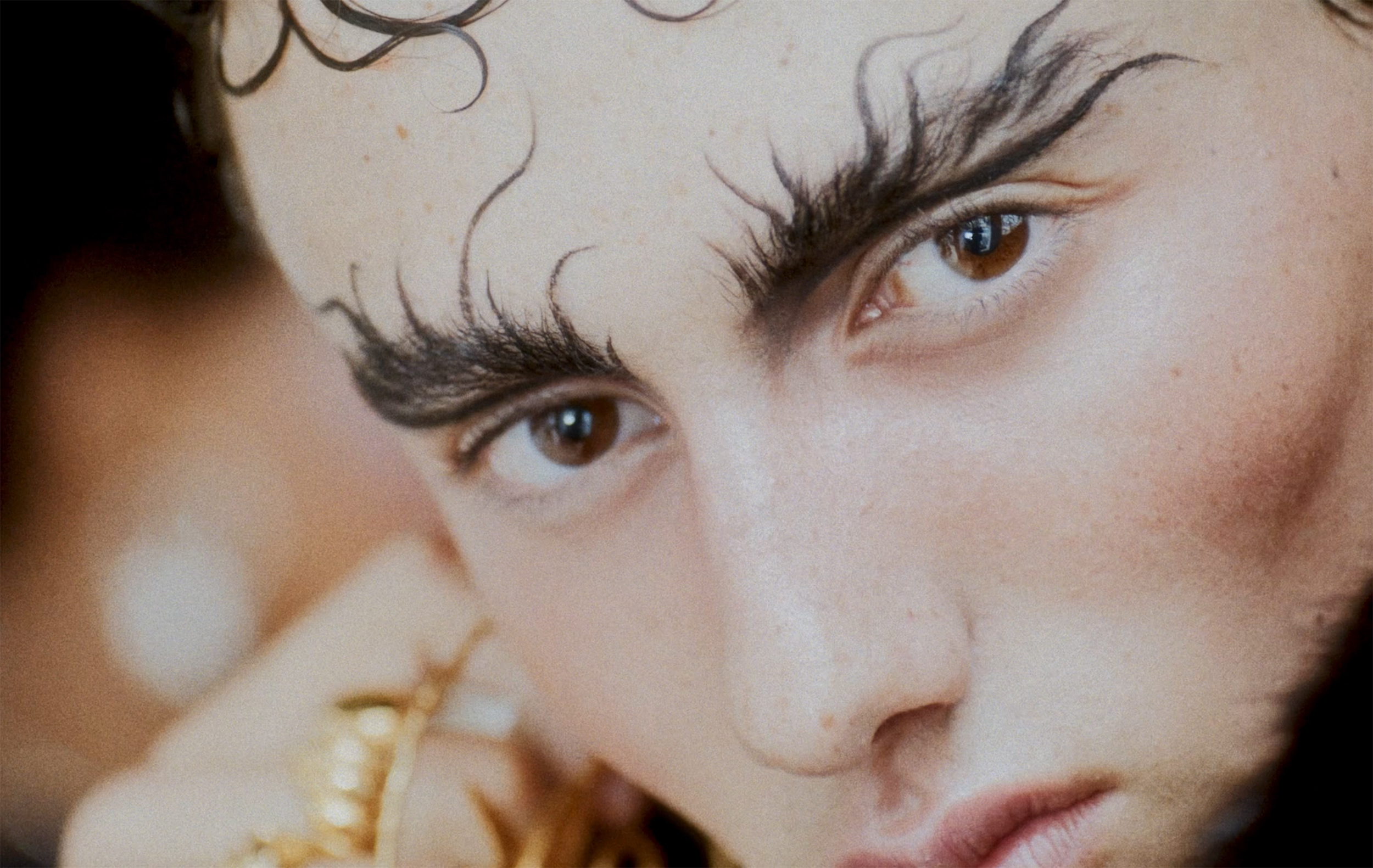 Stylish close-up portrait with bold, creative eyebrows and intense gaze.