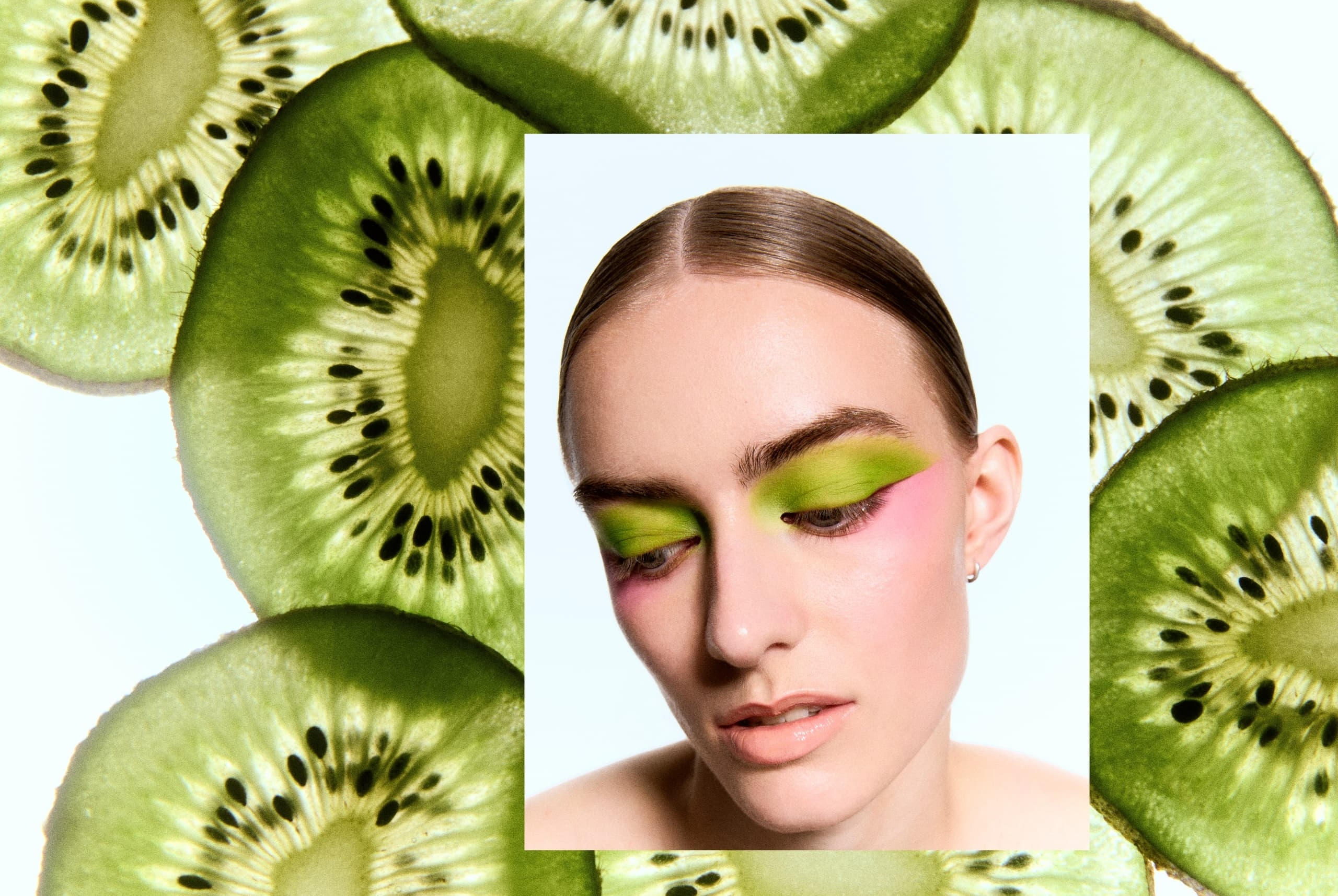 Woman with kiwi-inspired green eyeshadow surrounded by kiwi slices.