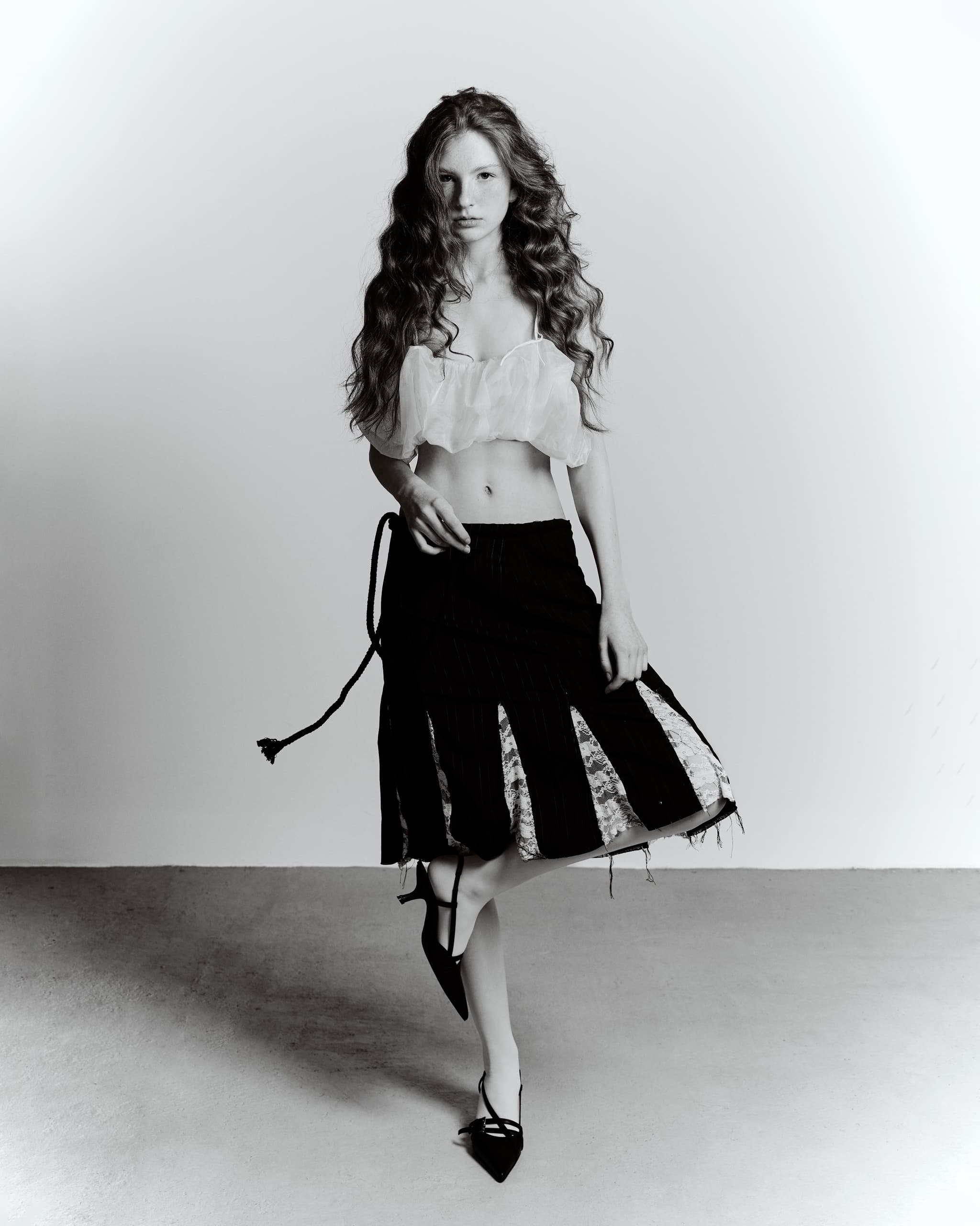 Model in stylish black skirt and white top posing with confidence.