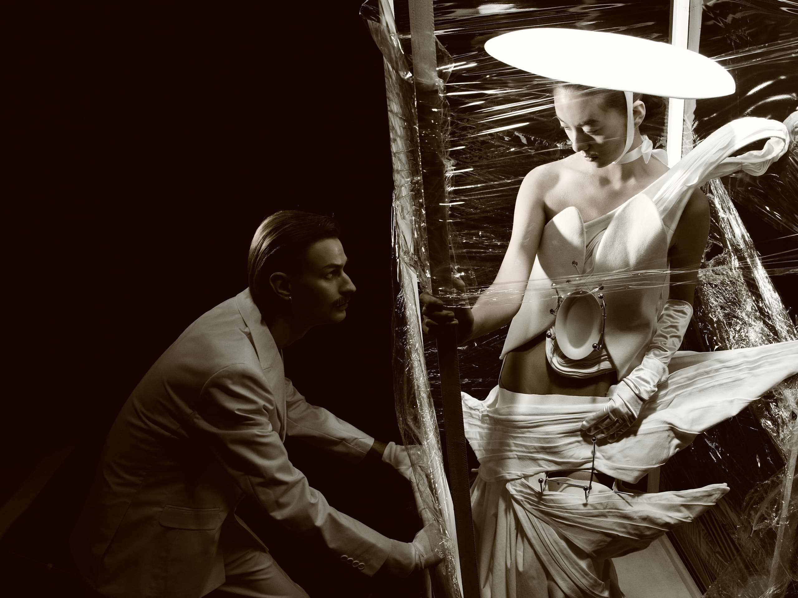 Futuristic fashion models in avant-garde outfits with dramatic lighting.