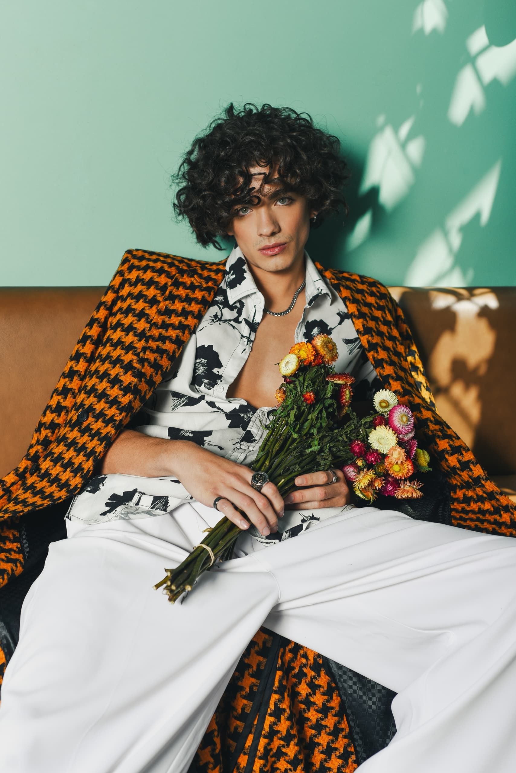 Fashionable individual in vibrant outfit holding colorful flowers.