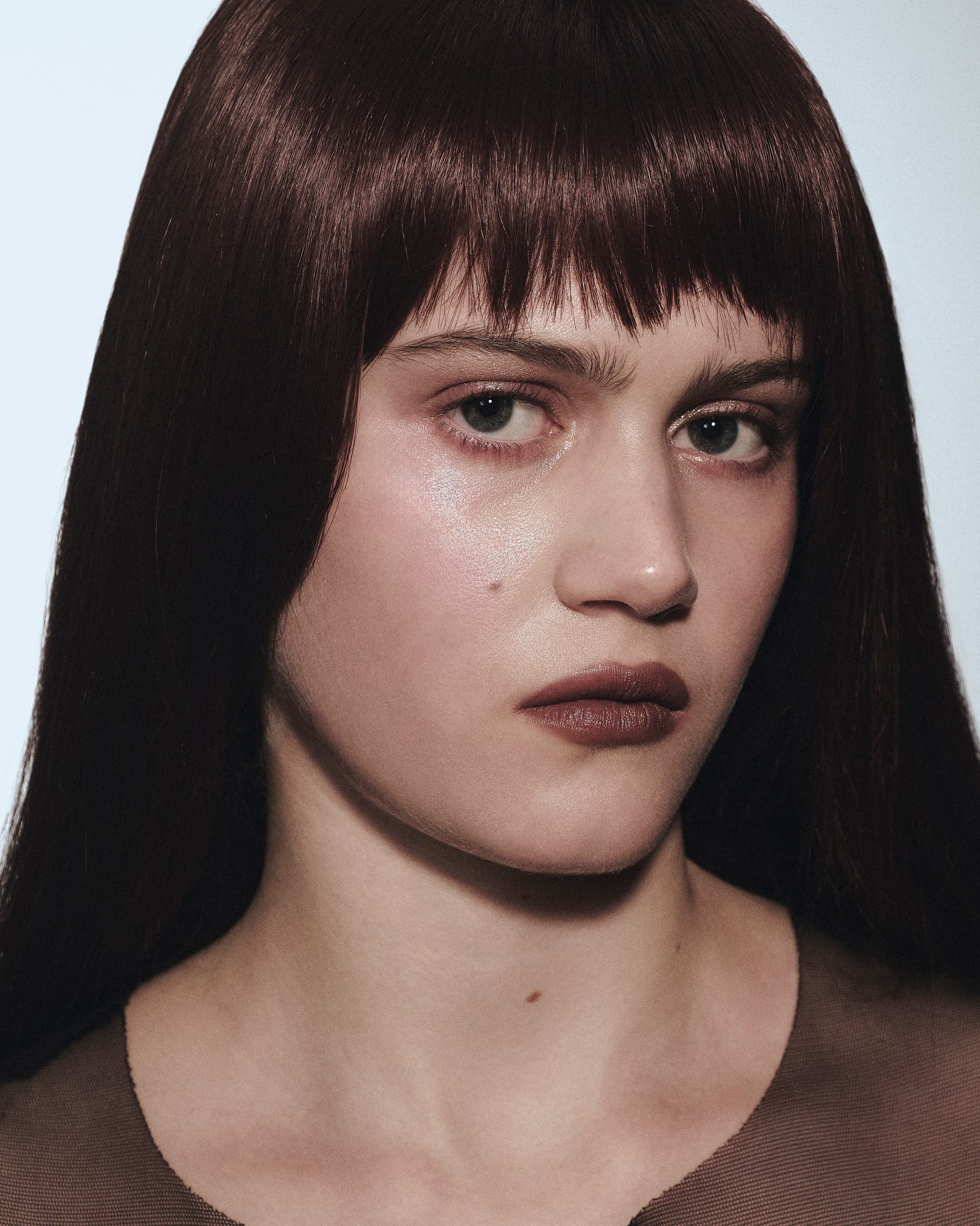 Portrait of a person with brown hair and bangs, showcasing a neutral expression.