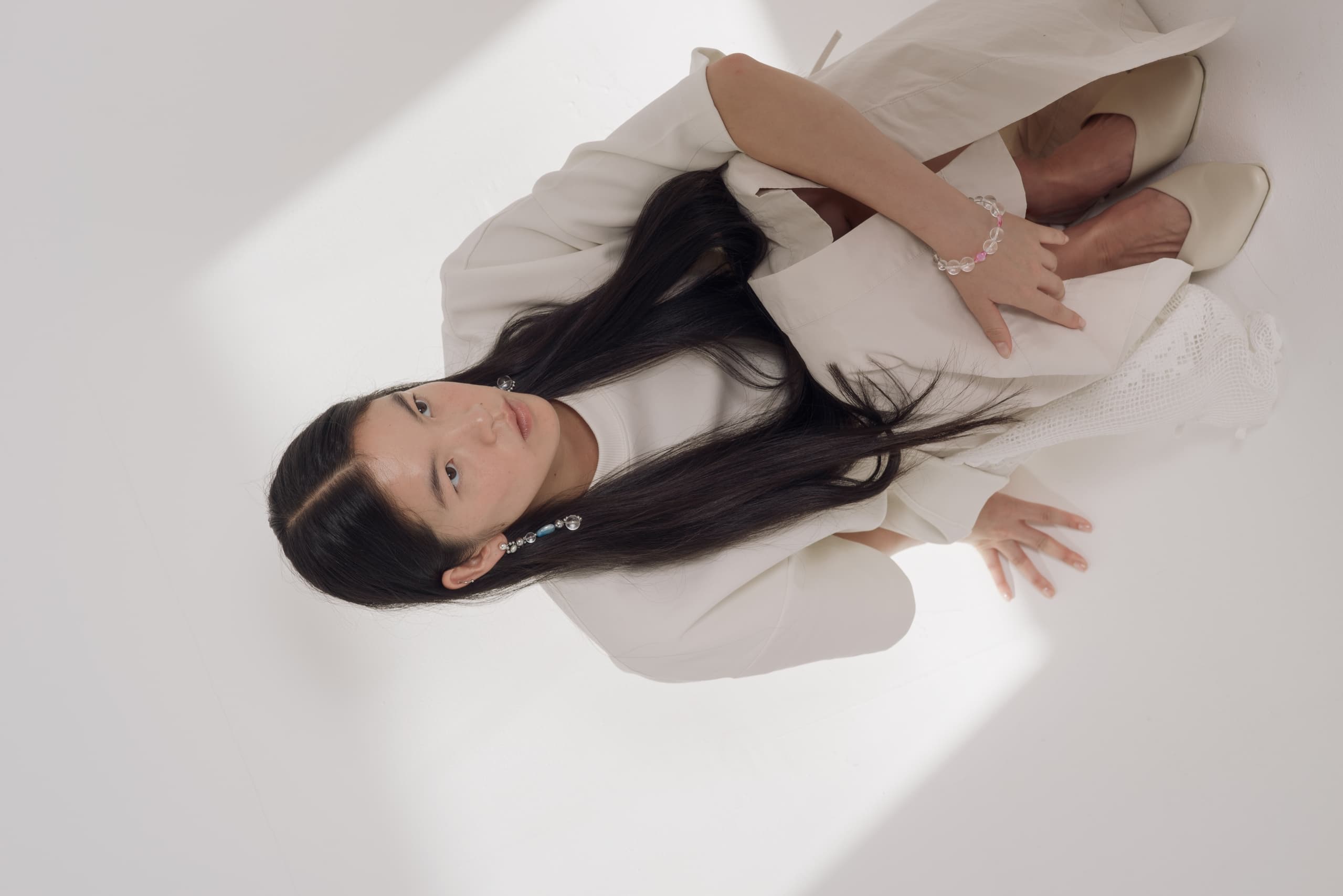 Woman in elegant white attire sitting on the floor, viewed from above.