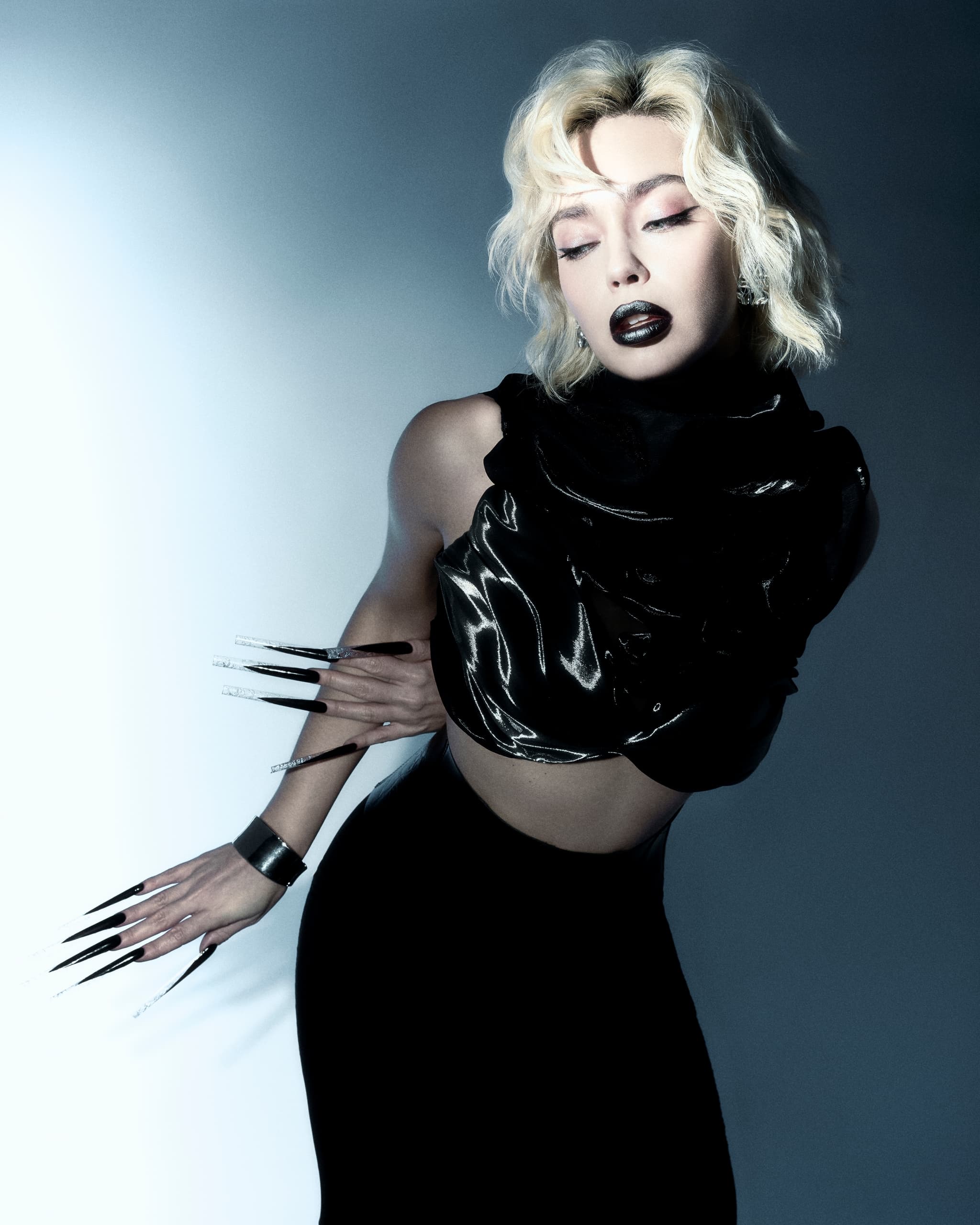 Edgy fashion portrait: woman with long black nails, platinum hair, black outfit.