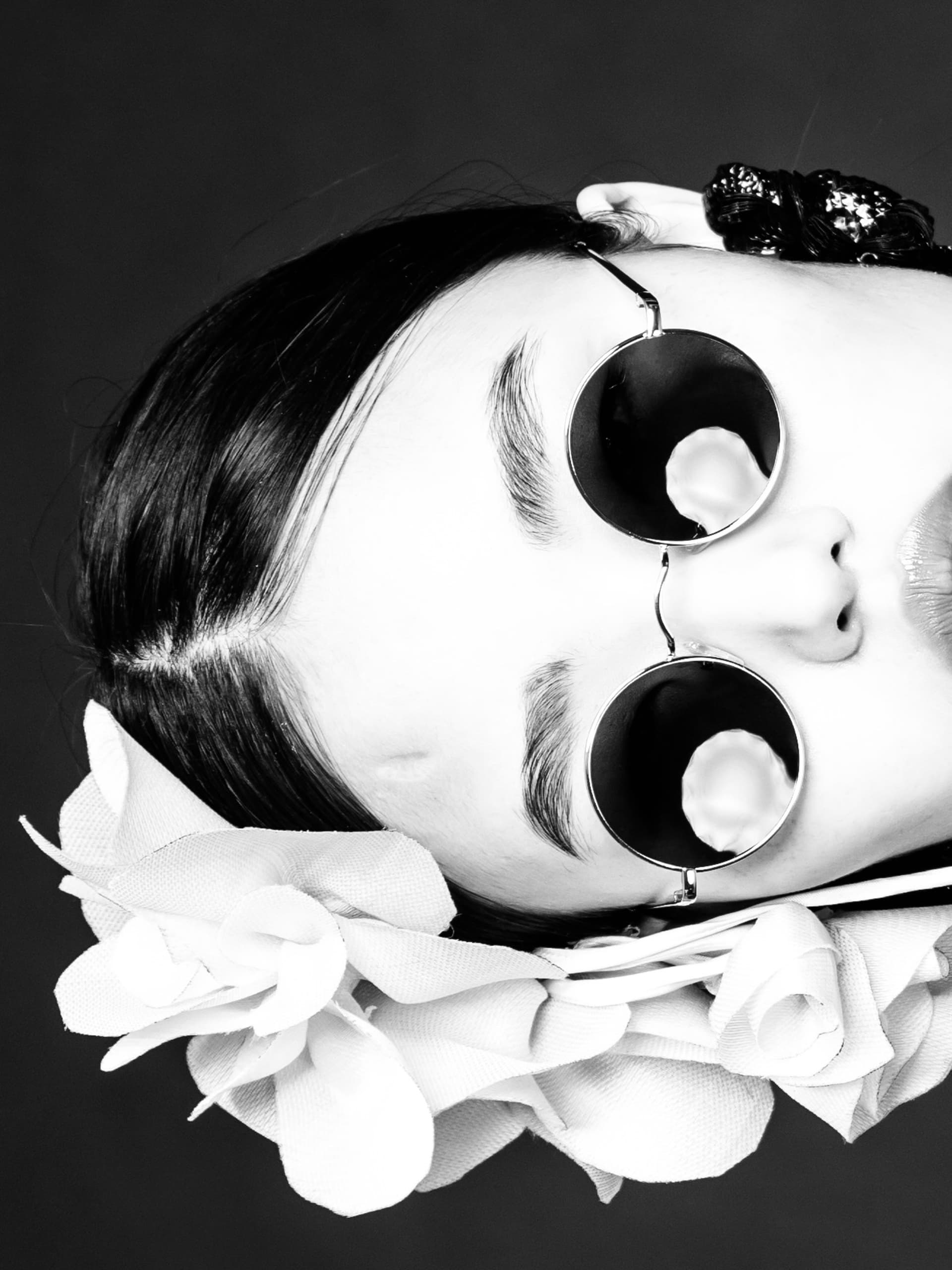 Woman in sunglasses with flower headpiece in black and white portrait.