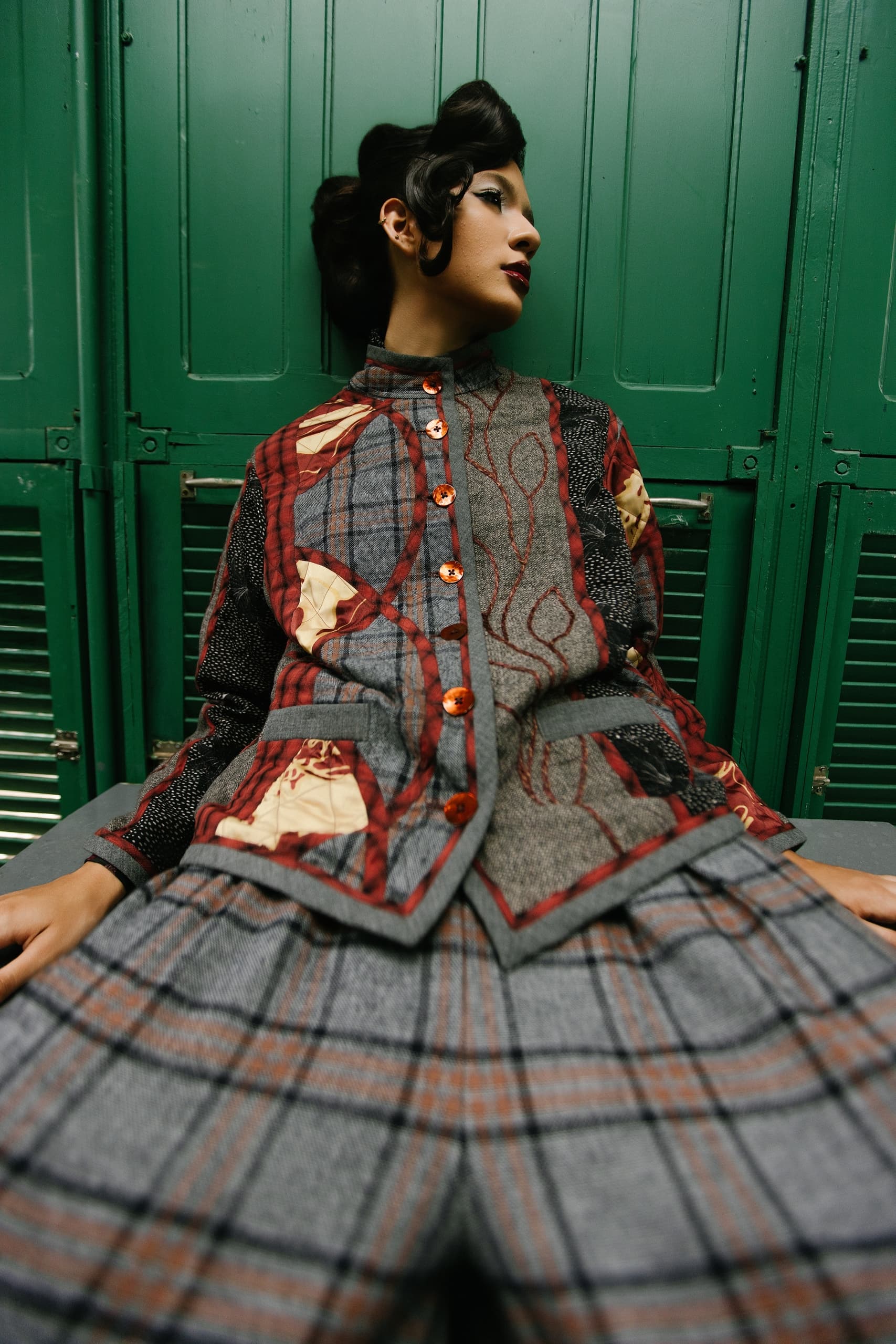 Fashion model in patterned outfit against green lockers.