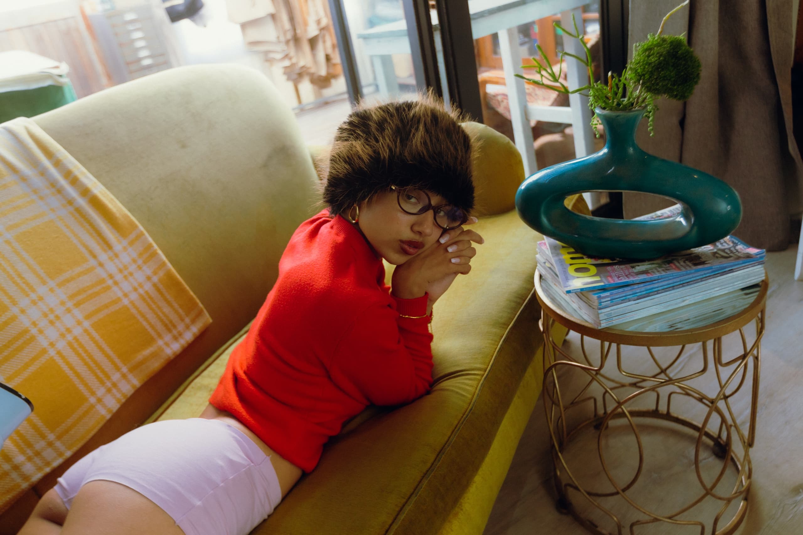 Person lounging on yellow couch in cozy, stylish room with colorful decor.