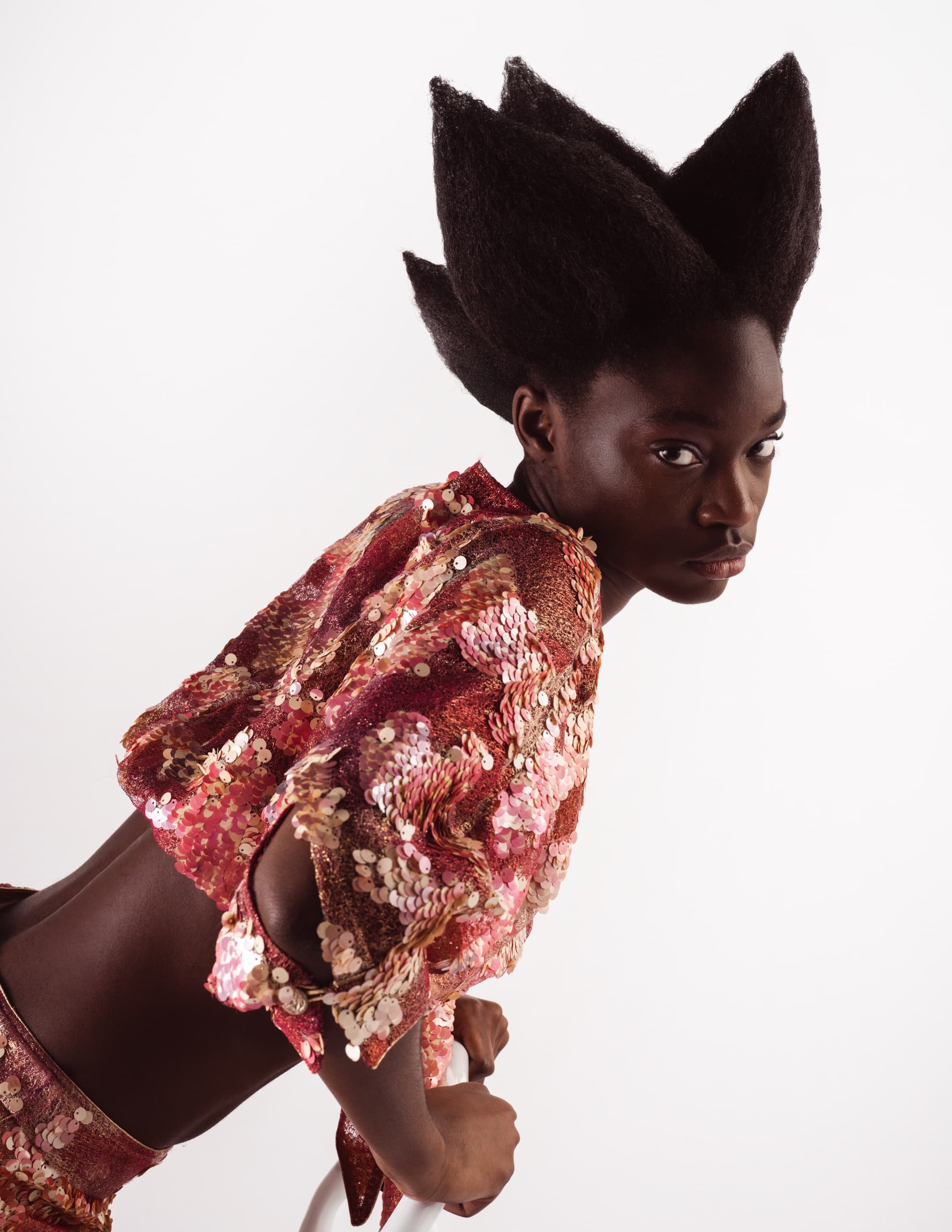 Futuristic hairstyle and sequin outfit on fashion model showcasing unique style.