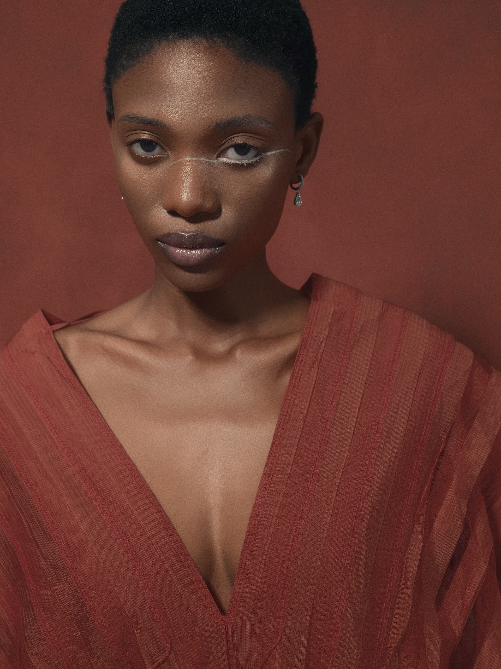 Stylish portrait of woman in red outfit against textured background.